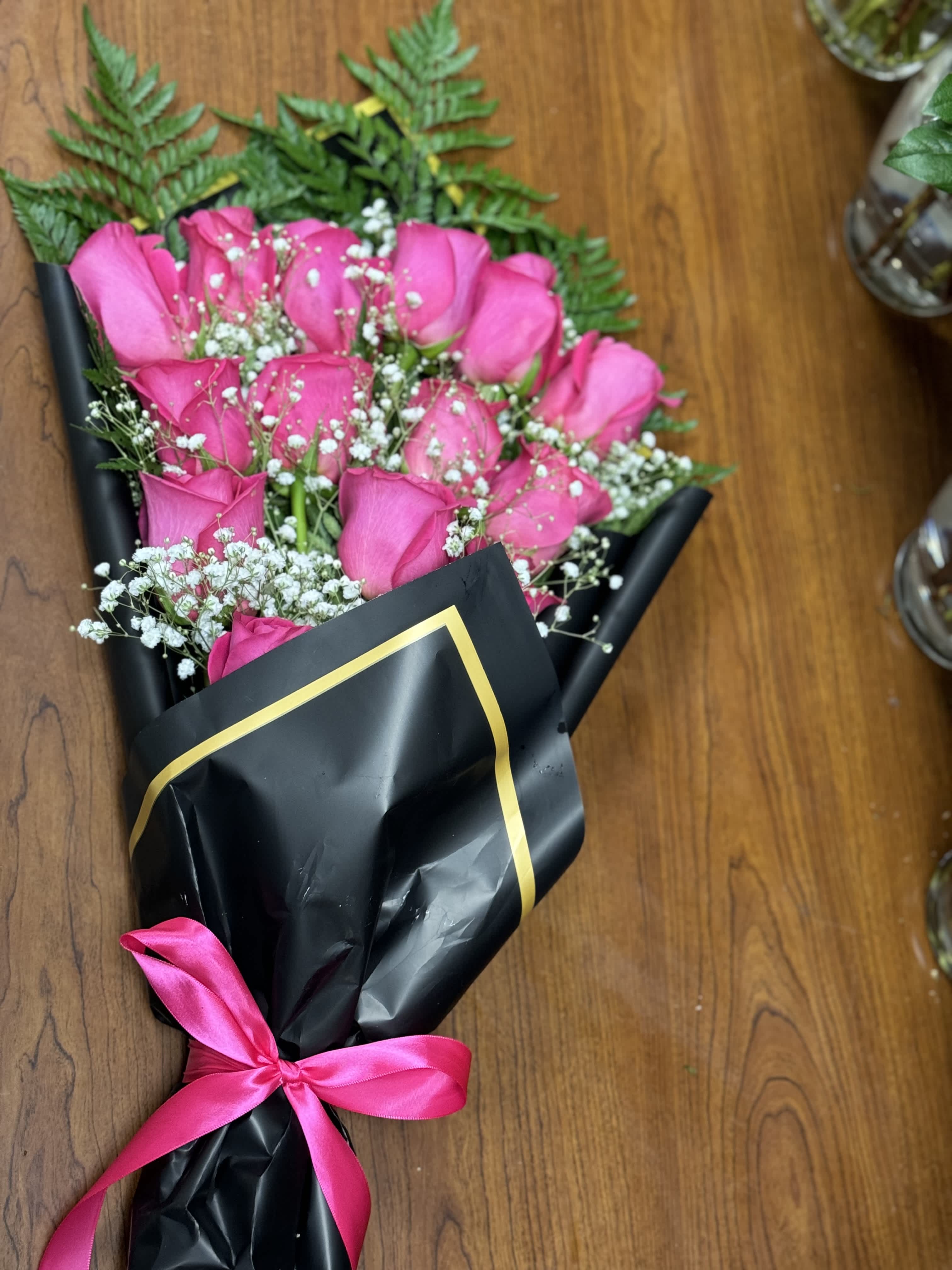 Bouquet of pink roses wrapped in black paper with a pink ribbon