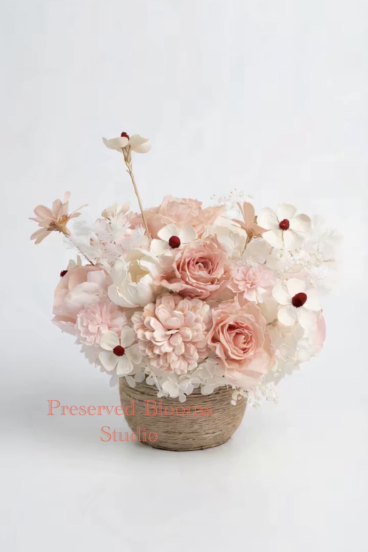 Pastel peach and white flower arrangement in a woven basket