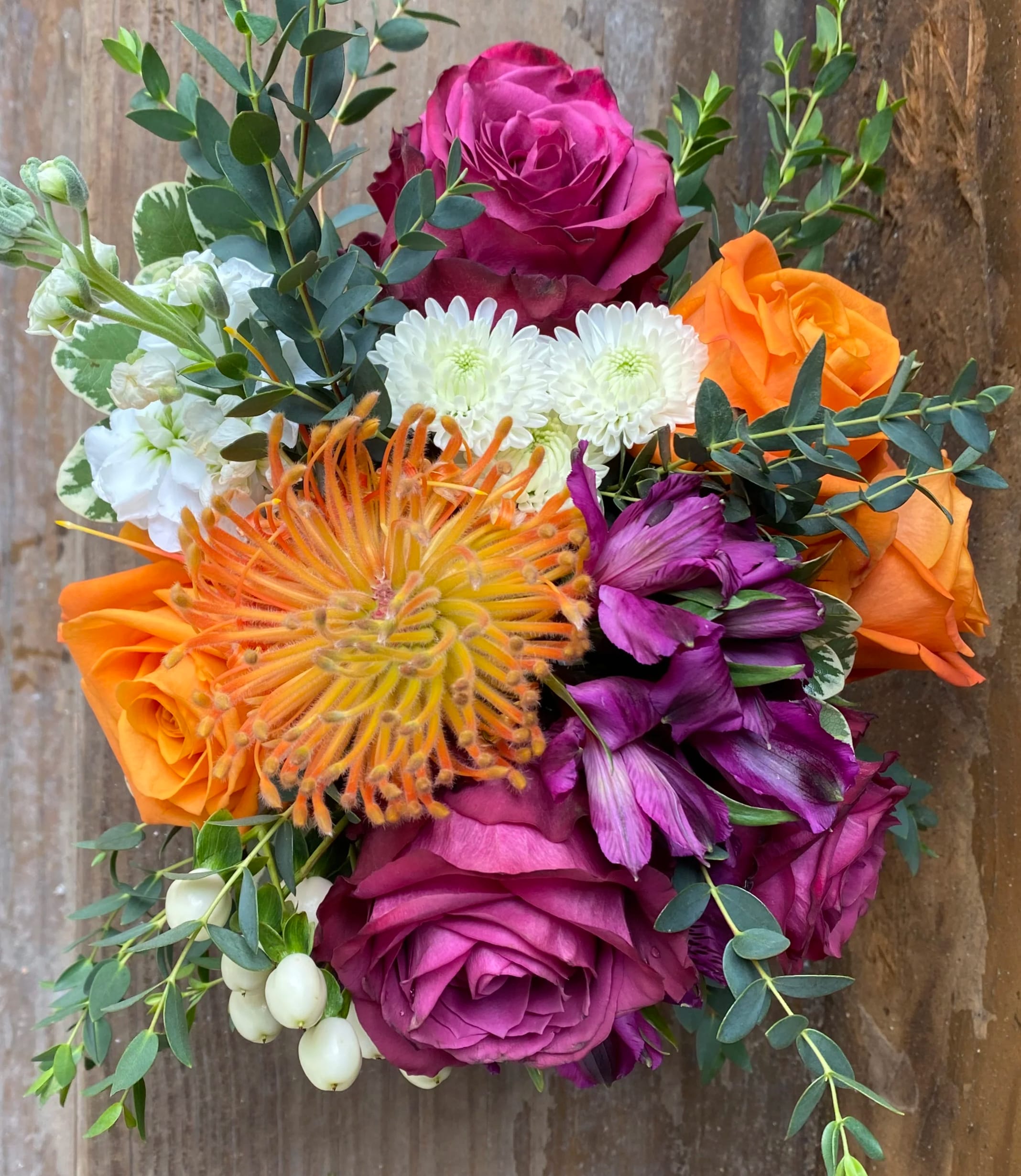 Bouquet of orange, magenta, and white flowers with eucalyptus foliage