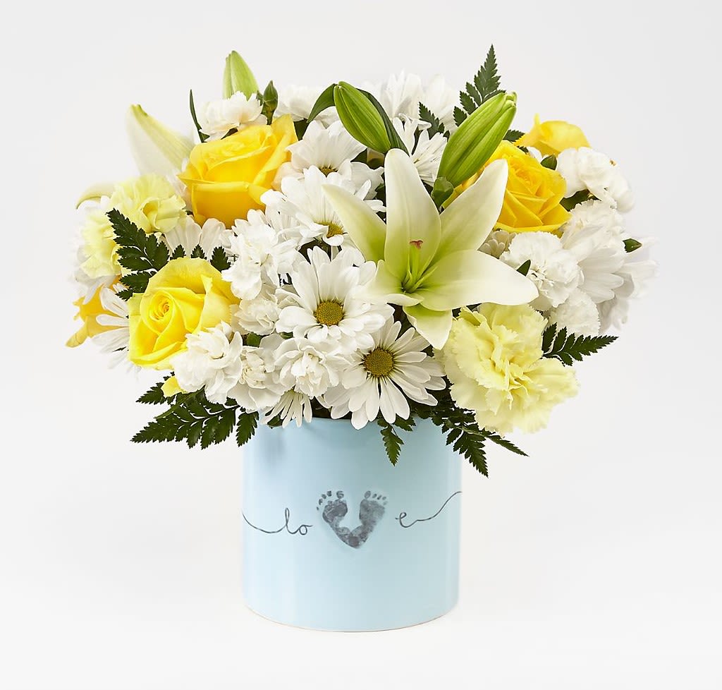 Baby Boy Bouquet - Sunny yellow roses and crisp white lilies come together in this cheerful flower arrangement designed as a Baby Boy bouquet-perfect for new arrivals, baby showers, or a bright new-baby congratulation. The soft blue cylindrical vase printed with a small footprint-and-heart motif, adding a sentimental keepsake touch and tidy presentation that's easy to display.