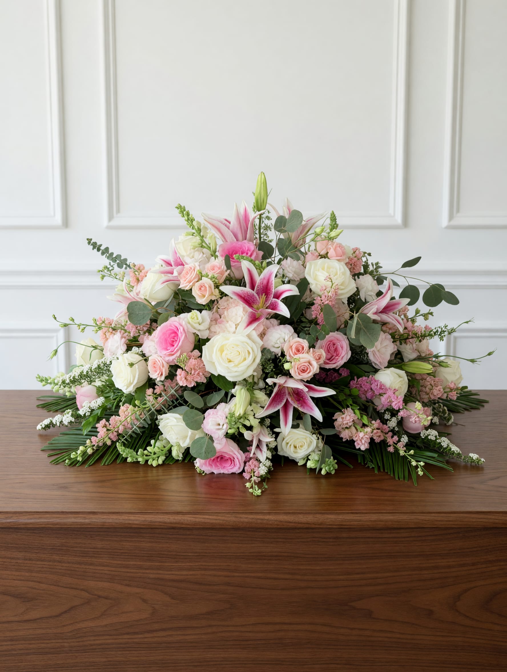 Pink Garden Casket Spray - An elegant garden-style casket spray featuring soft pink and white blooms with lush seasonal flowers and natural movement. Designed as a graceful final tribute for funeral and memorial services.