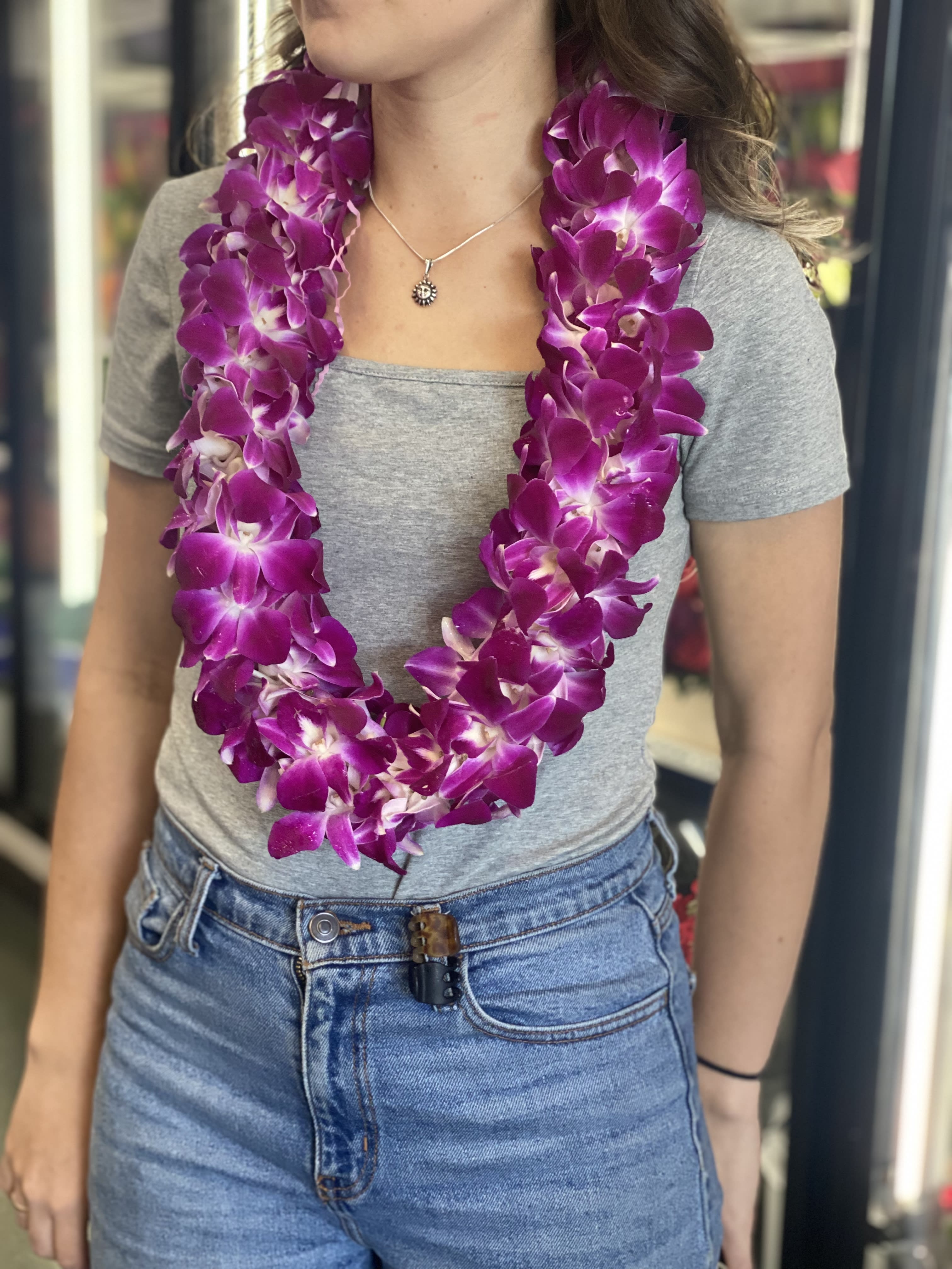 Woman wearing a purple orchid lei over a gray shirt