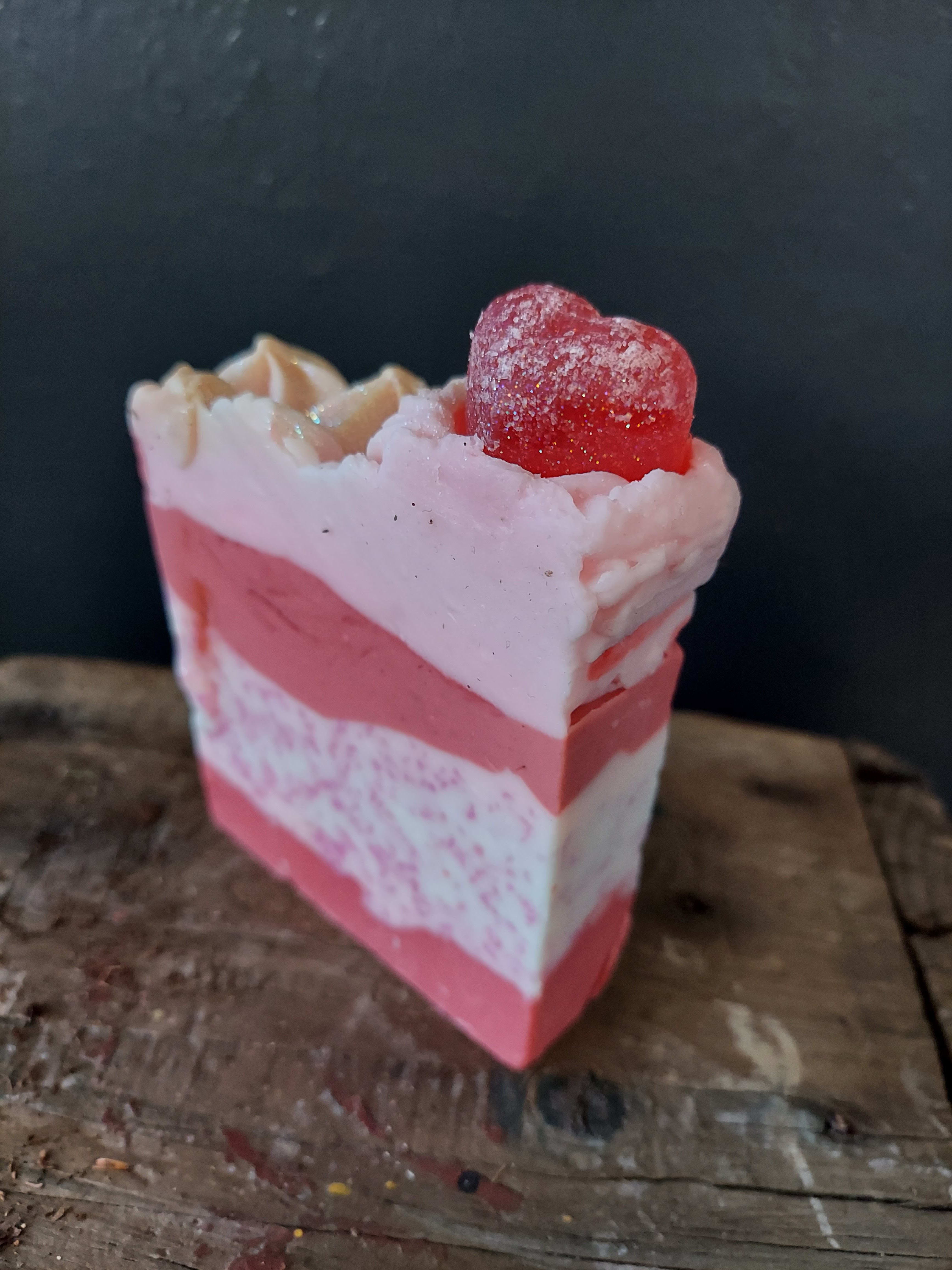 Pink layered soap bar topped with a red heart-shaped candy
