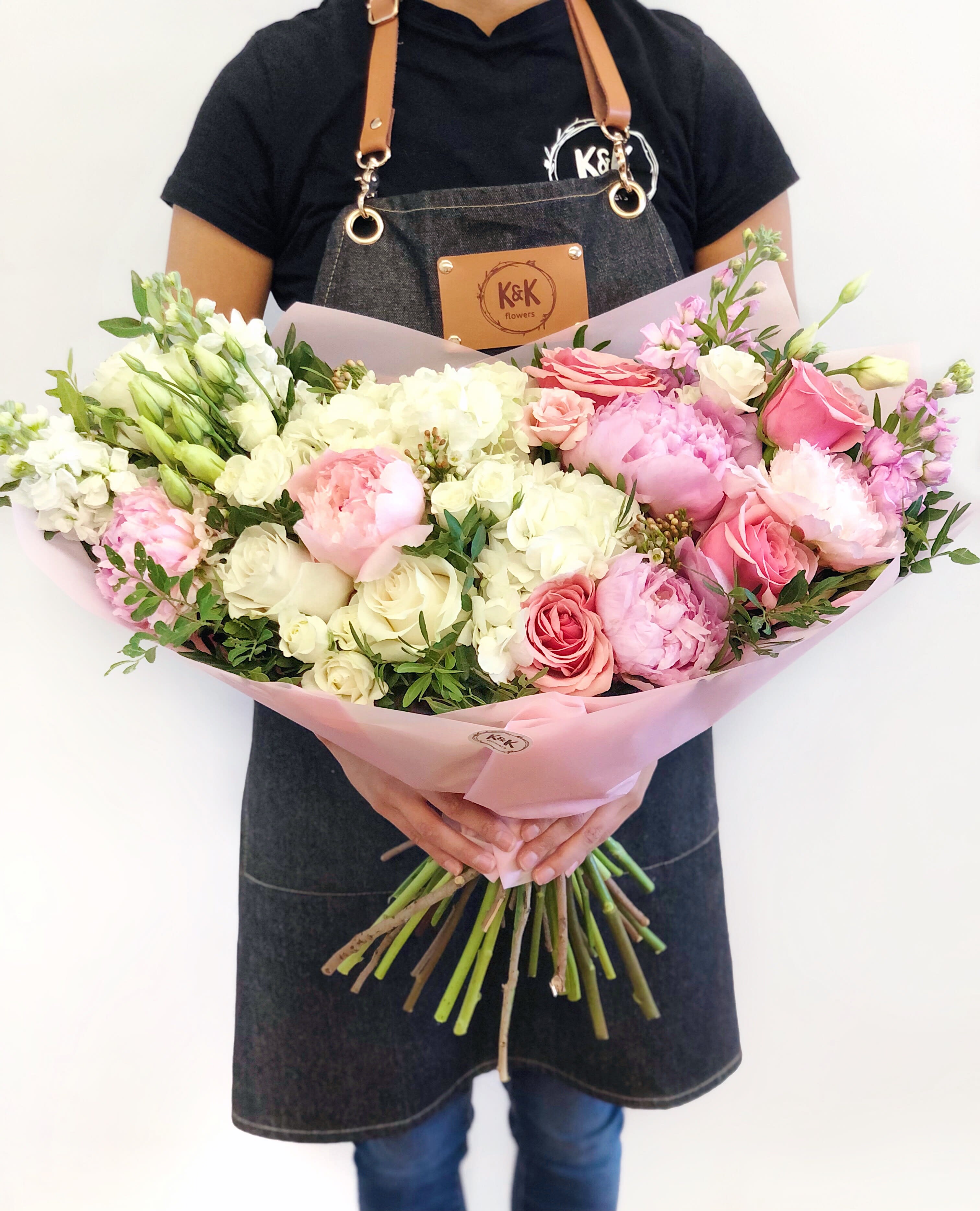 Large bouquet of pink and white flowers wrapped in pale pink paper