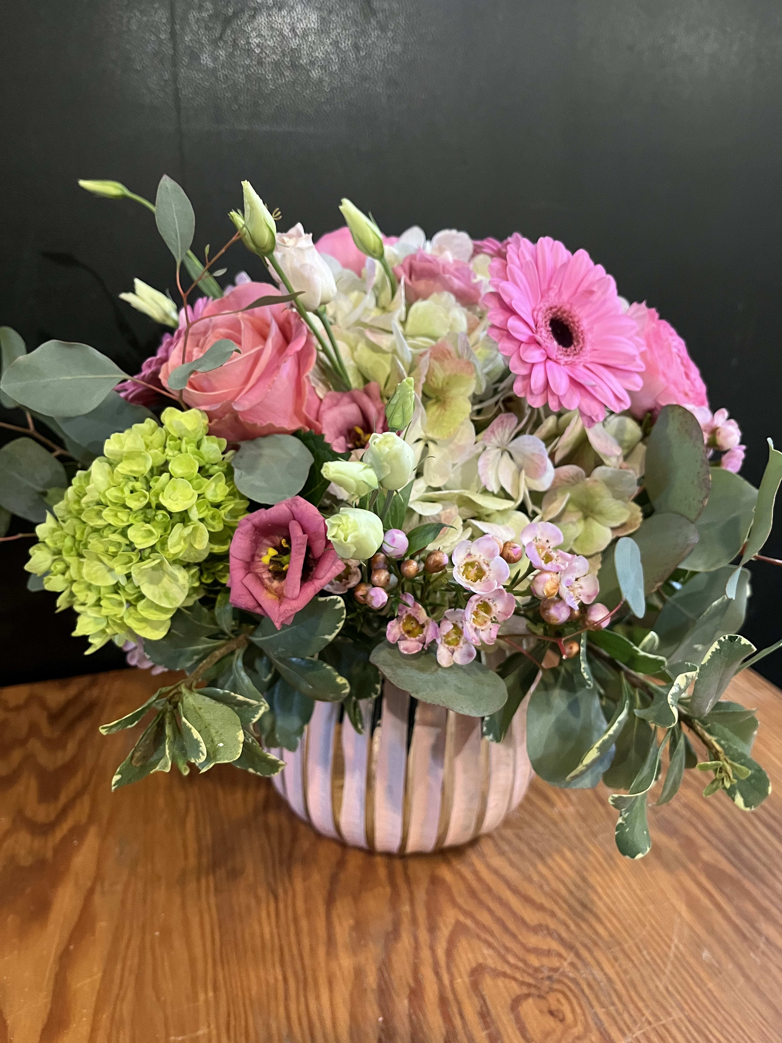 Pink and green mixed flower arrangement in a striped vase