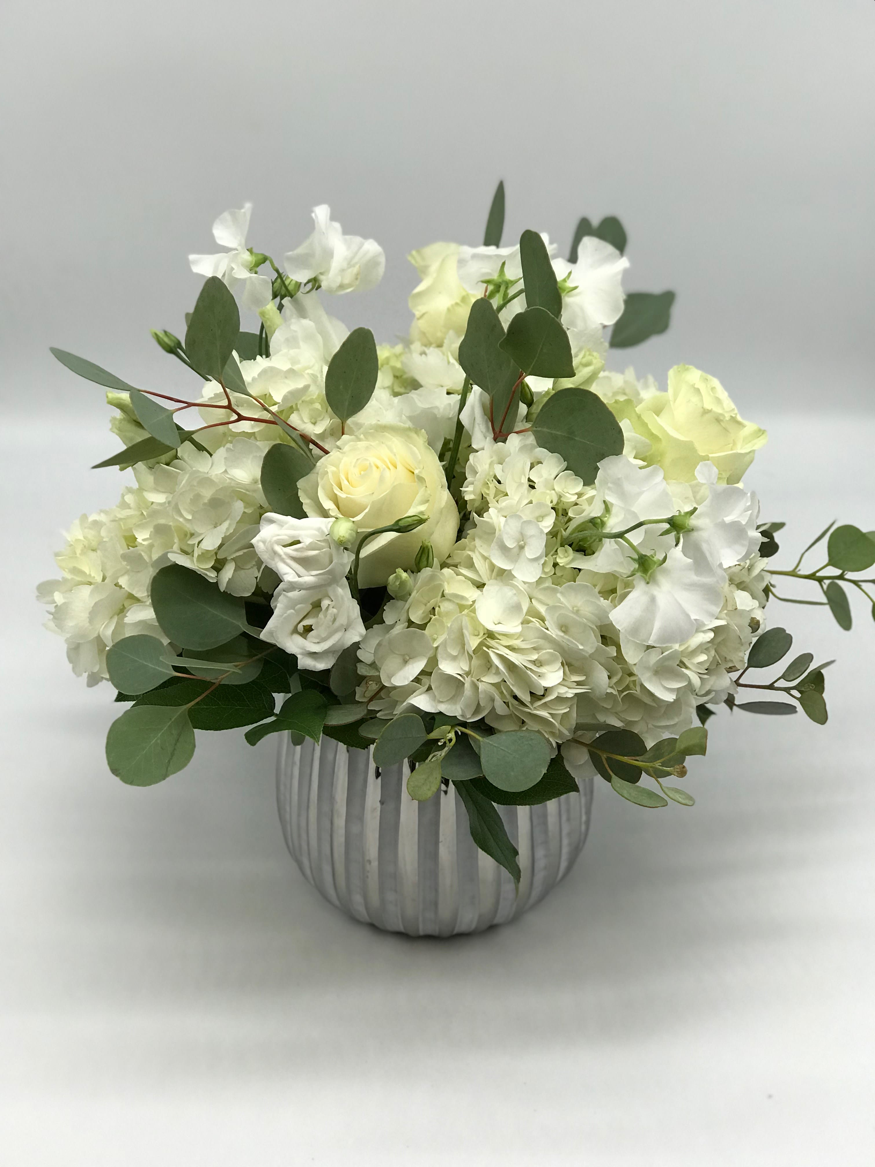 White roses and hydrangeas in a ribbed silver vase