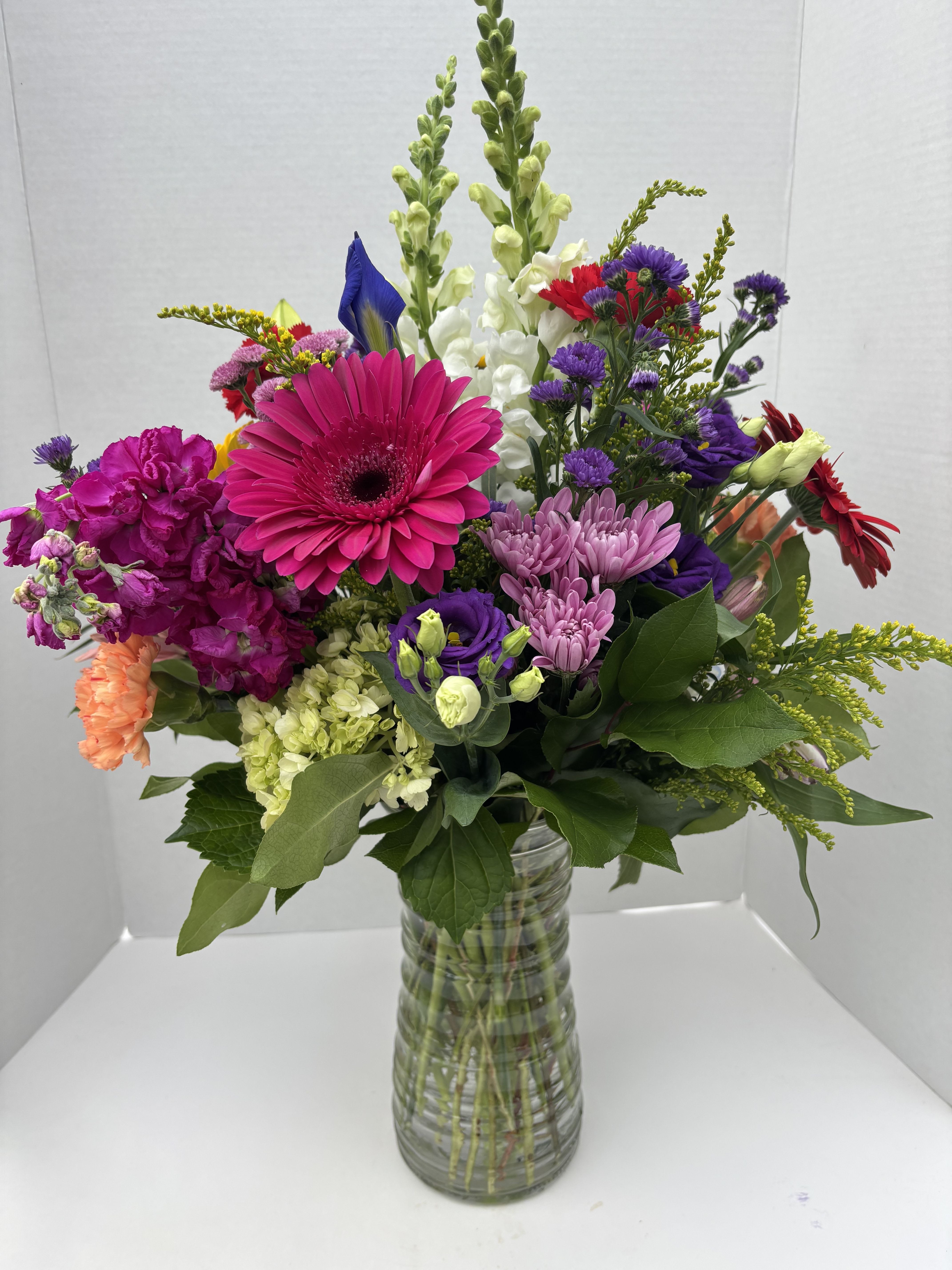 Colorful mixed bouquet in a clear glass vase with gerbera daisies and snapdragons