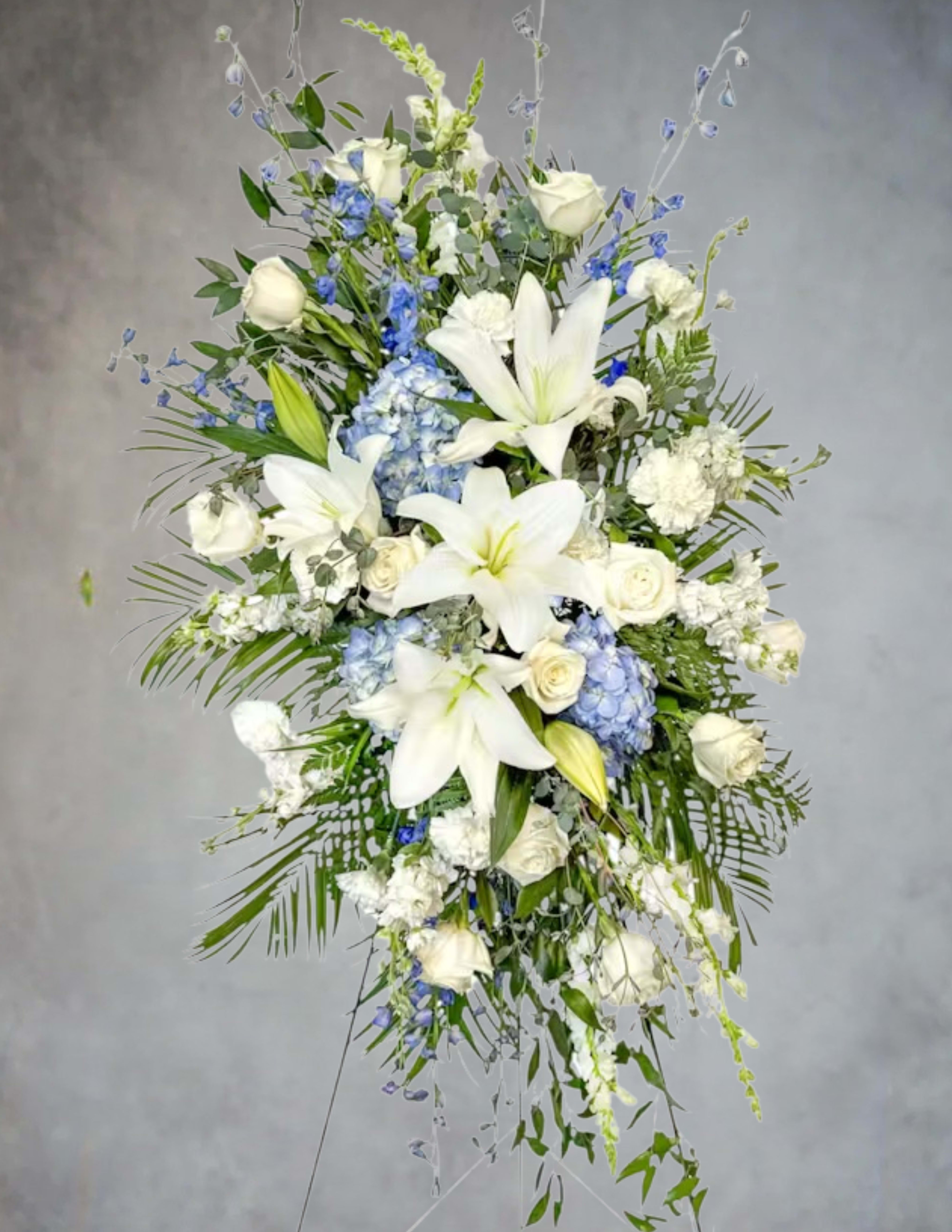 Tall white floral spray with lilies, roses, and blue accents