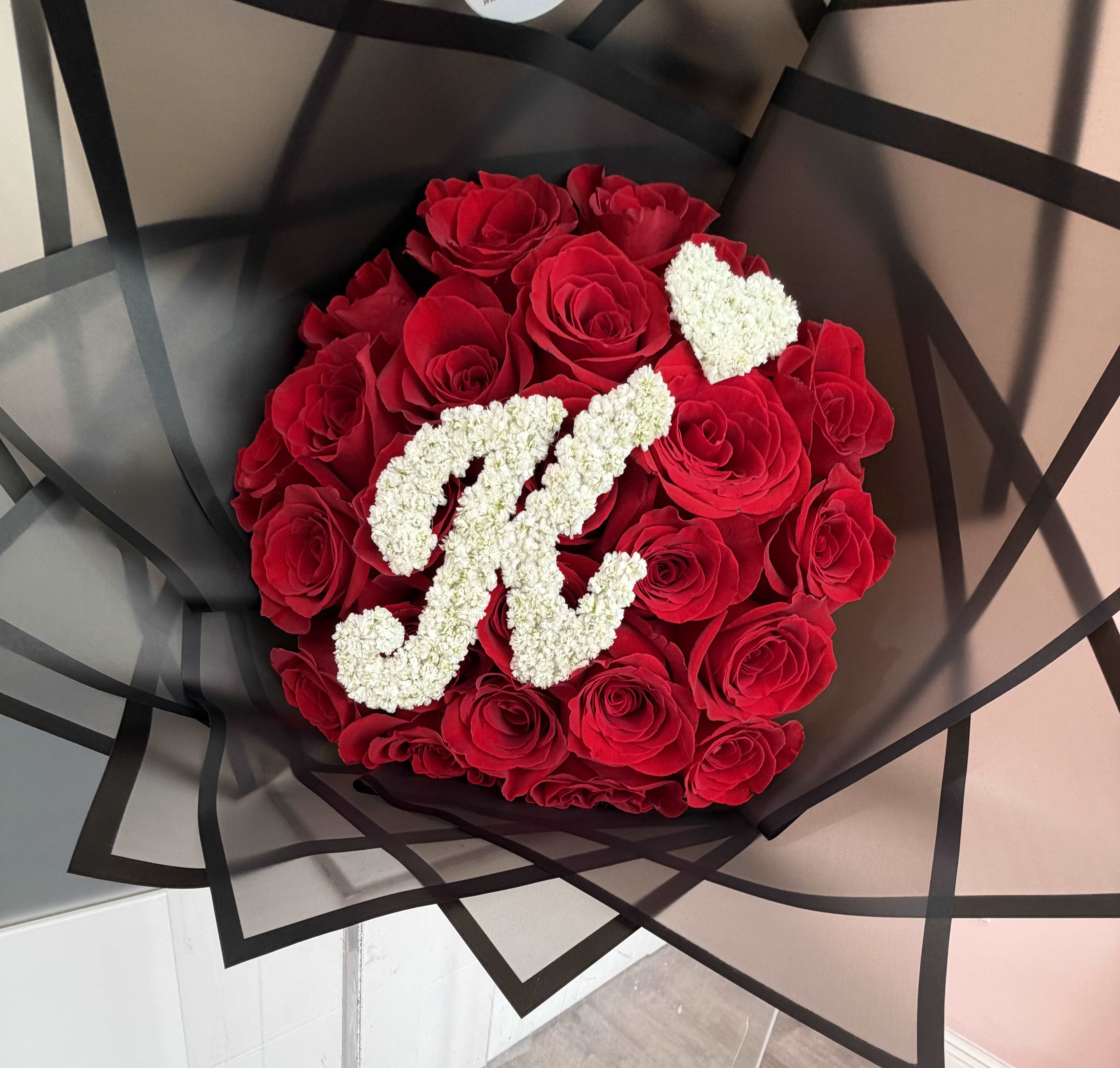 Initial Rose Luxe Bouquet - Make a statement with our Initial Love Rose Bouquet, a luxurious arrangement of premium red roses beautifully hand-designed and finished with a custom floral initial letter and heart. The initial and heart are crafted from delicate white baby breath blooms and placed at the center, creating a timeless and personalized touch.  Perfect for anniversaries, birthdays, Valentine’s Day, engagements, or just because—this bouquet is designed to impress and leave a lasting impression.  Details:     •    Premium fresh red roses     •    Custom floral initial + heart (letter of your choice)     •    Handcrafted by our floral designers     •    Wrapped in elegant modern waterproof paper   Personal, romantic, and unforgettable.  *** Advance Notice Required: Custom floral initial arrangements require a minimum of 1 day advance notice to ensure availability and proper design.