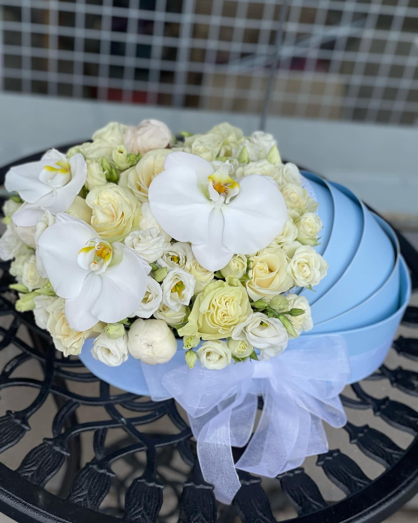 White rose and orchid bouquet in a light blue hatbox with a sheer ribbon