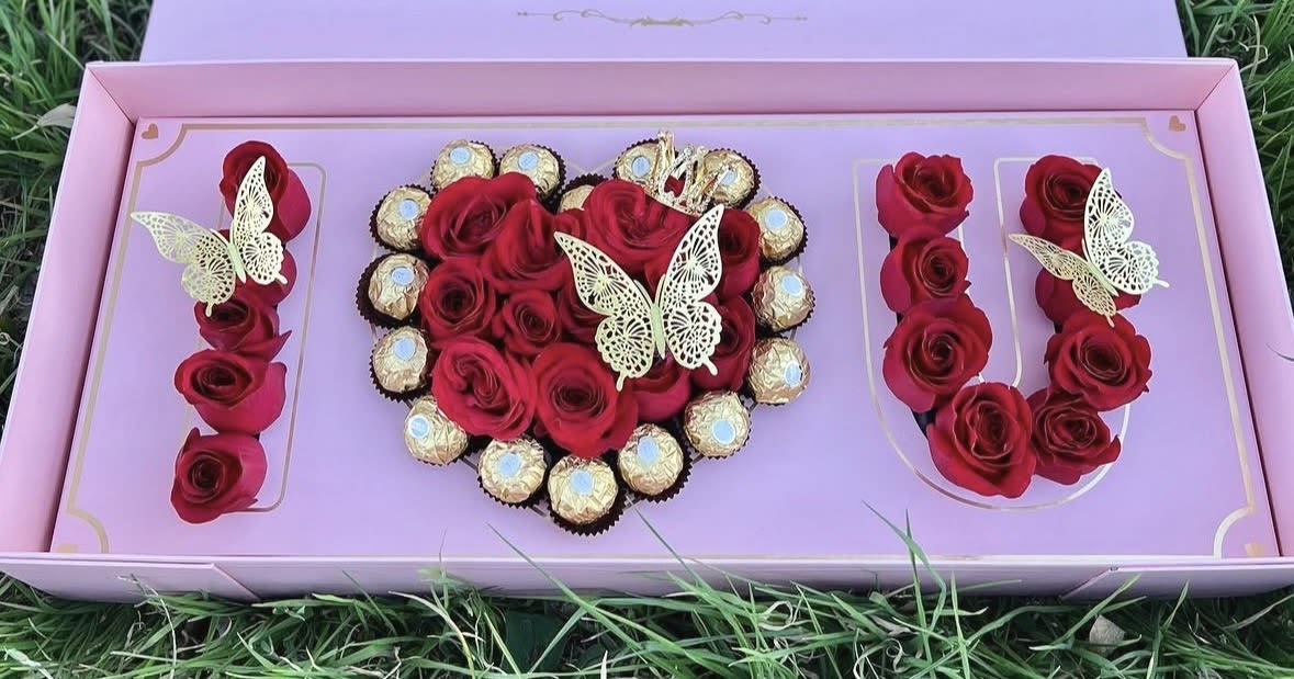 Love you with all my heart - A heart of red roses set inside a pastel pink presentation box-this flower arrangement for an anniversary or romantic gift spells out "I U" with rose clusters so the person you're thinking of feels truly adored. The arrangement reads as a love-themed bouquet and keepsake all at once: red roses form a central heart while additional rose groupings create the letters on either side, and delicate decorative butterflies float through the composition for a whimsical, romantic touch.  Colors of red, pink and touches of white mingle against a lavender interior panel to give depth and softness; individually wrapped chocolates ring the heart for a celebratory, gift-box finish. The set arrives in a pastel pink gift box with chocolates and decorative butterfly picks already arranged, making it an immediate visual impact and an easy, ready-to-present surprise.  Perfect for anniversaries, Valentine's Day, or any moment you want to say "I love you" with flair, this keepsake presentation is designed to delight the recipient the moment they open it. Order to have the box delivered ready to gift-no additional arranging needed-and mention any delivery notes at checkout for special timing or messages.