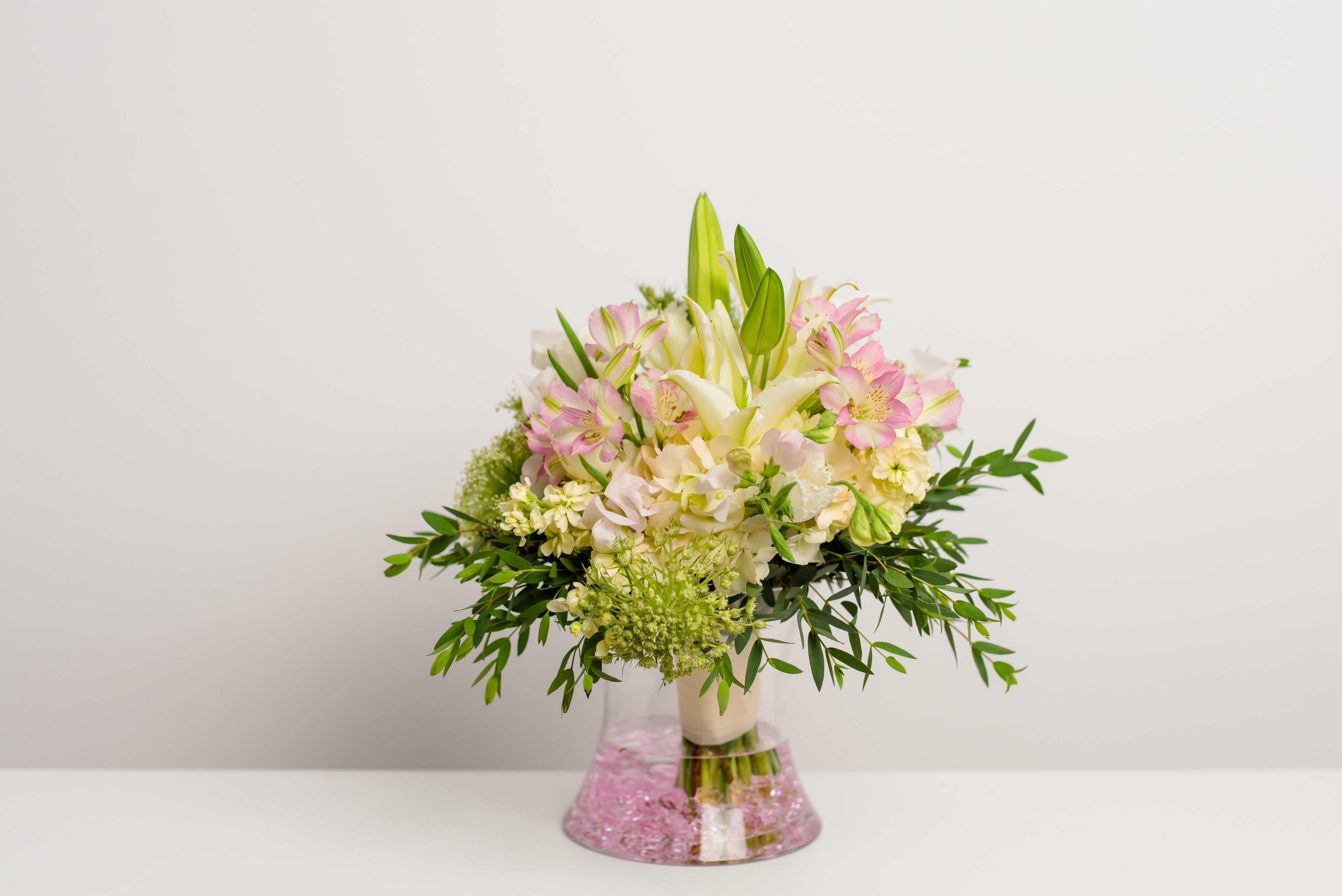 Pink and white bouquet with lilies in a clear vase
