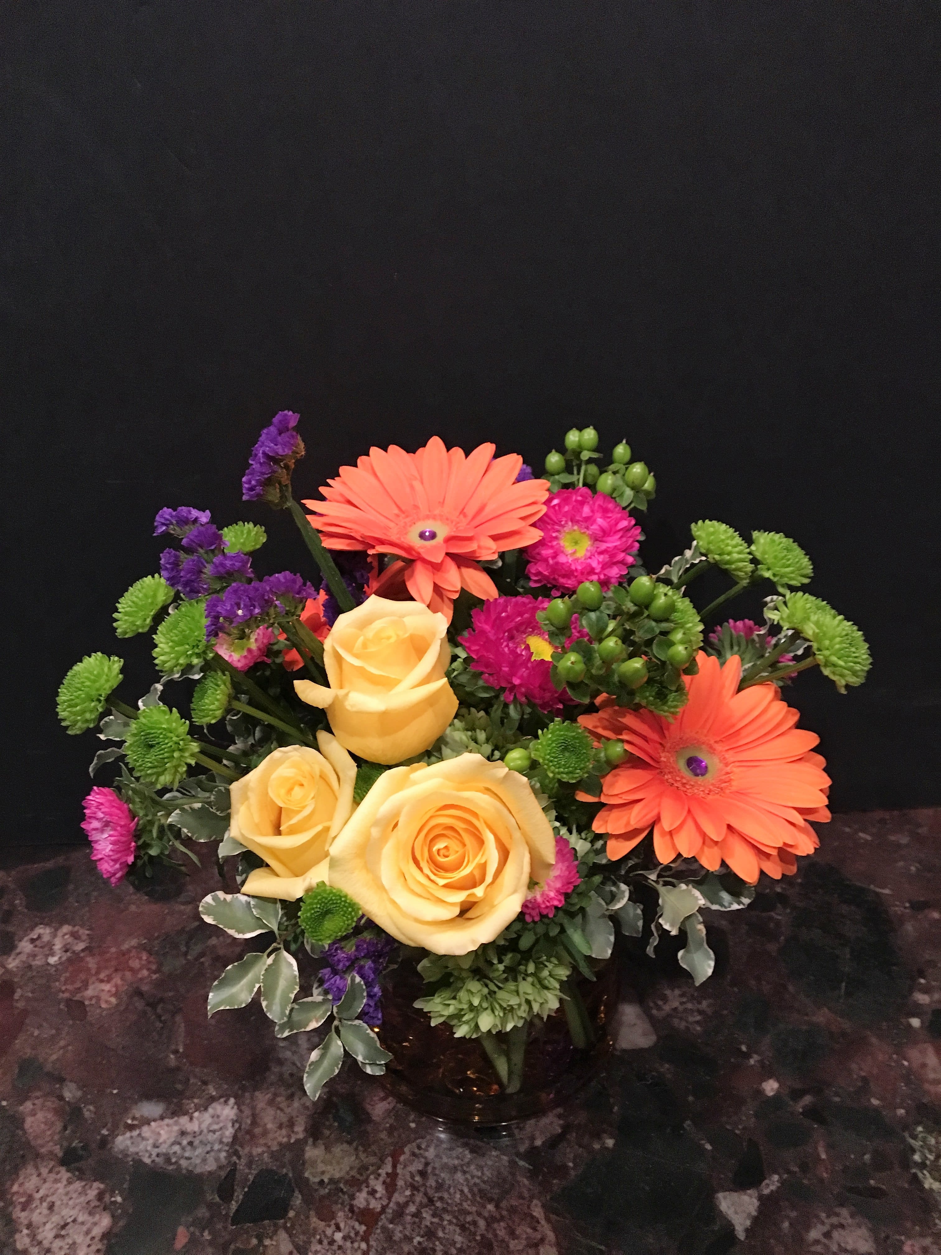 Bouquet of yellow roses, orange gerbera daisies, and purple accents
