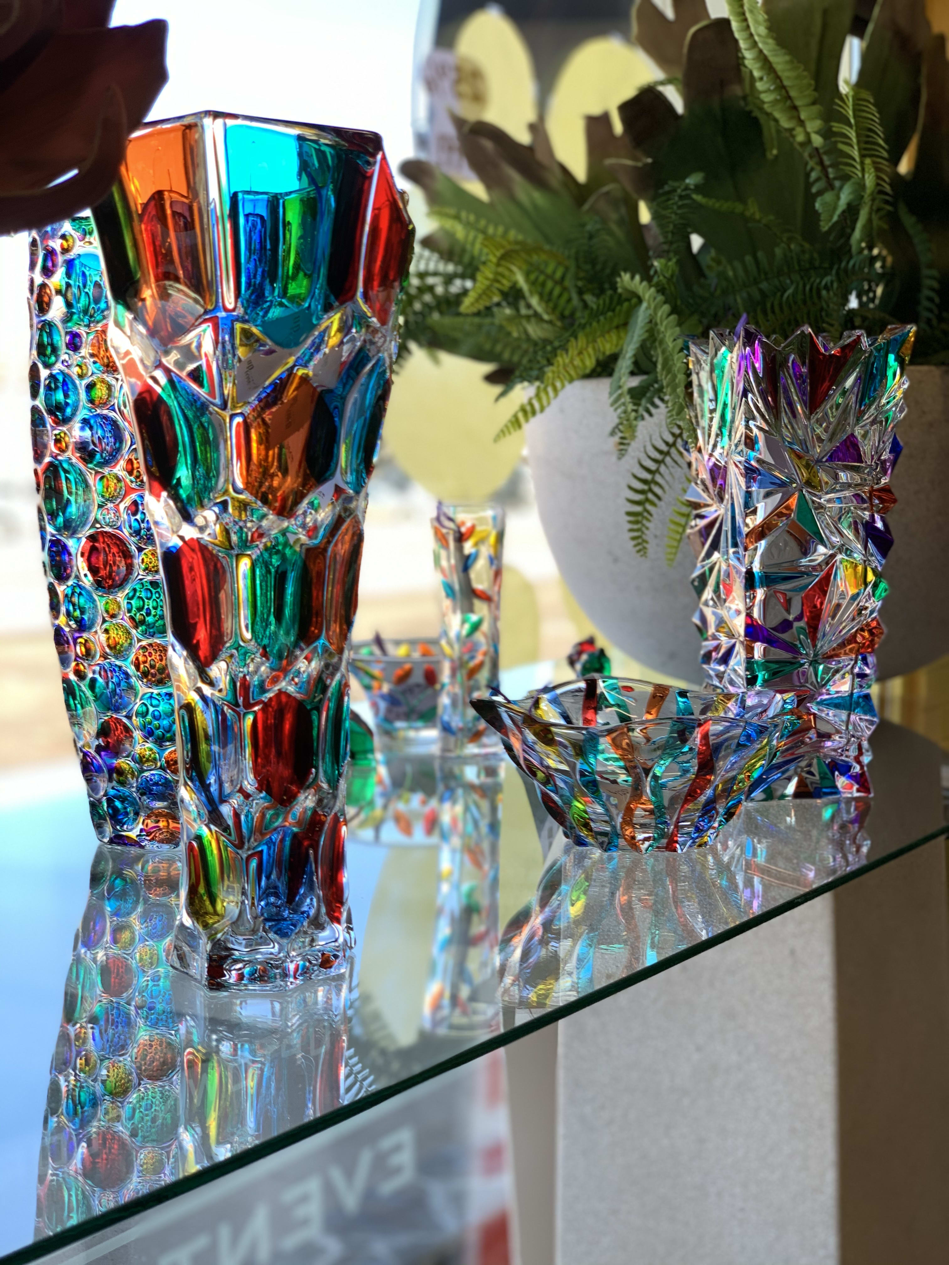 Colorful glass vases on a shelf with a potted fern