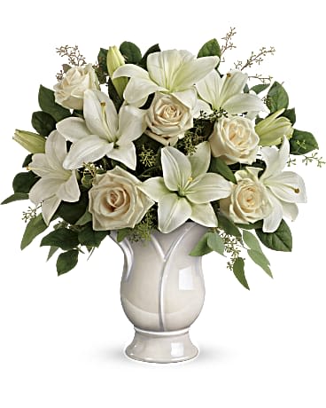 White lilies and cream roses arranged in a white vase