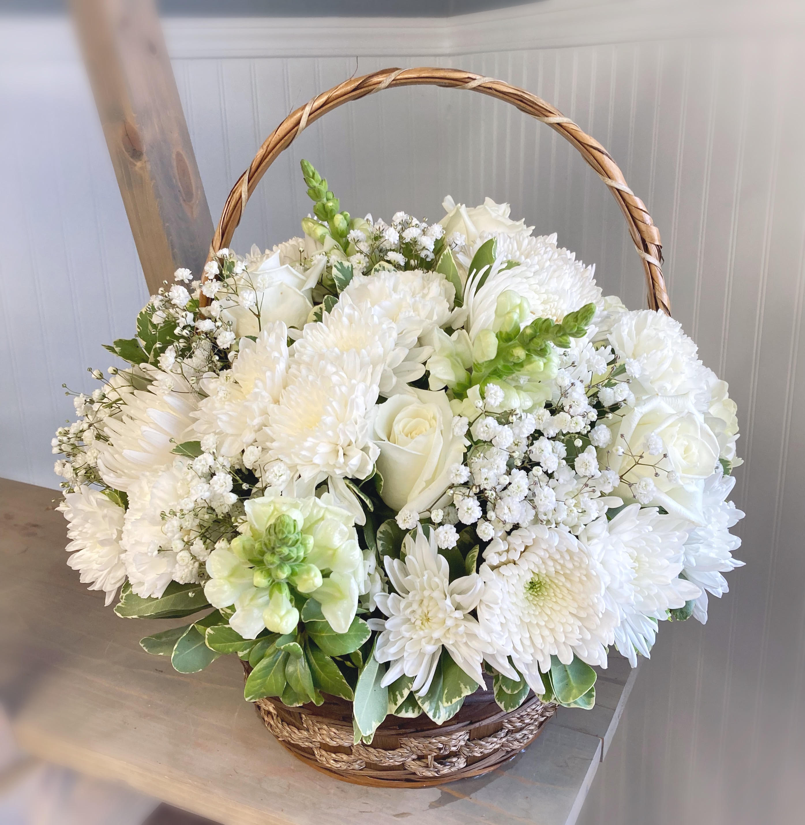 White floral basket arrangement with roses, chrysanthemums, and baby's breath