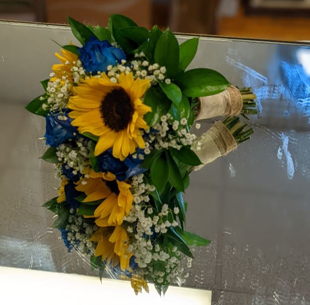 Bouquet of yellow sunflowers and blue roses with white baby's breath