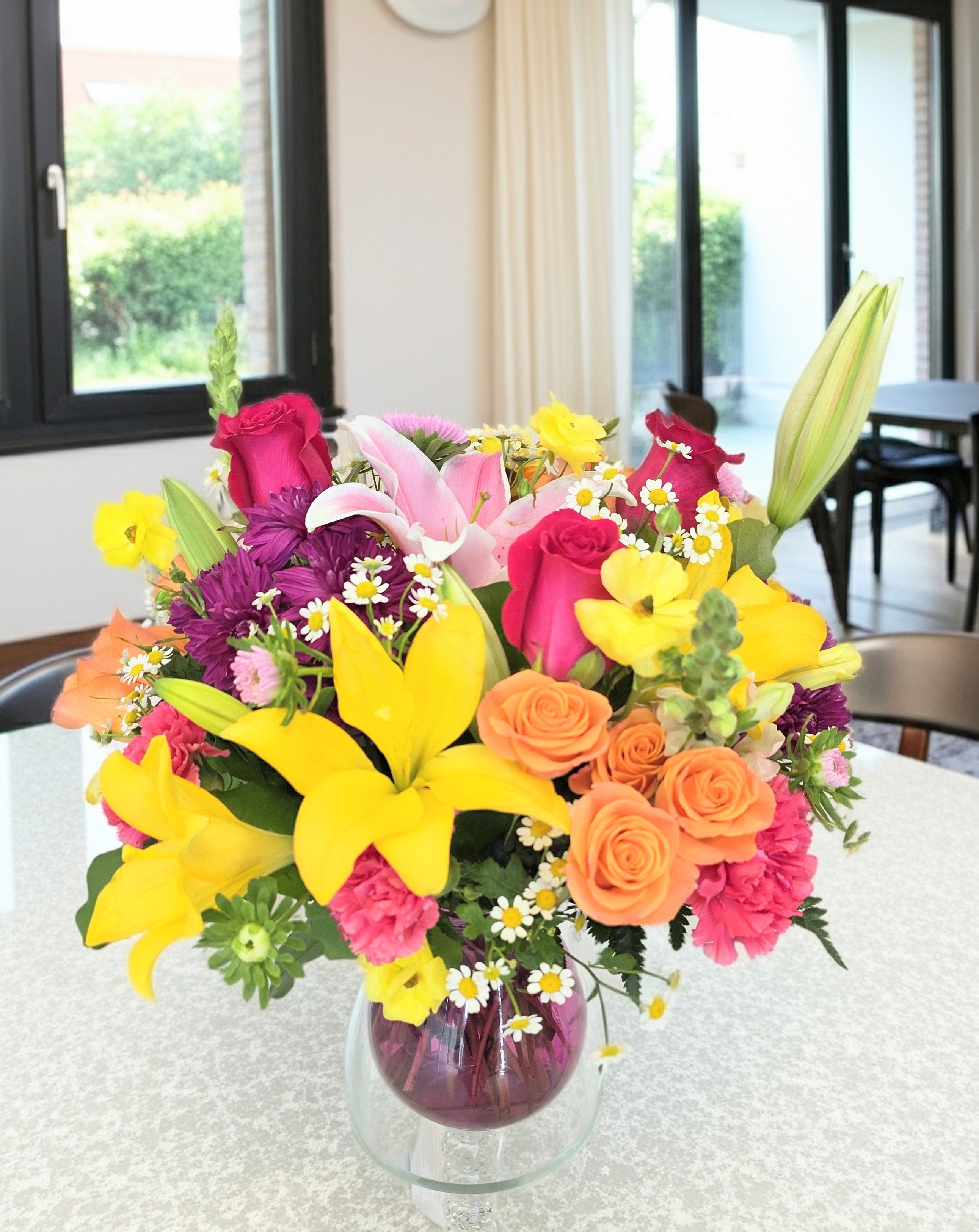 Celebrate The Moment   Bouquet - Bright yellow lilies take center stage in this Summer Fun bouquet, a lively birthday bouquet or just-because gift that reads as joyful and celebratory. The mix of hot pink and peach roses, vivid orange tones, and purple chrysanthemums pops against clusters of petite white daisies, so the person you're thinking of will feel instantly cheered and seen.