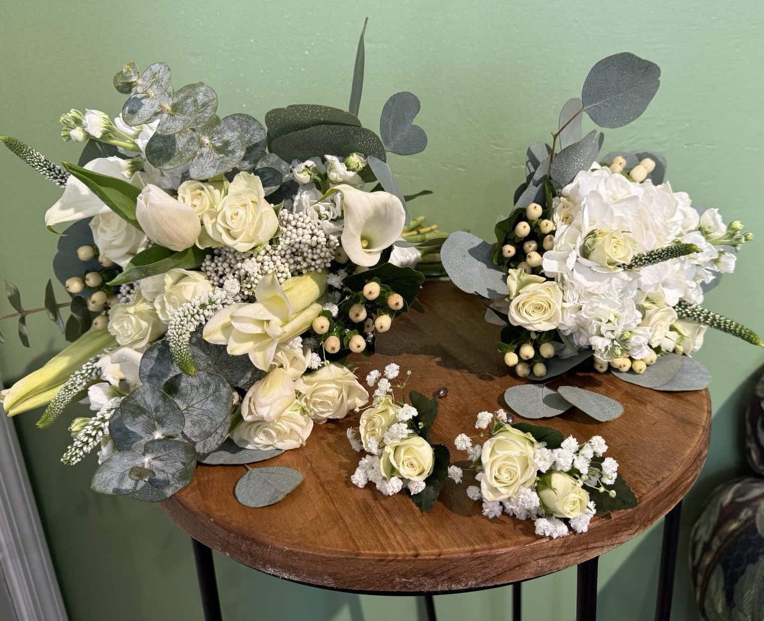 White rose and calla lily bouquets with eucalyptus on a table