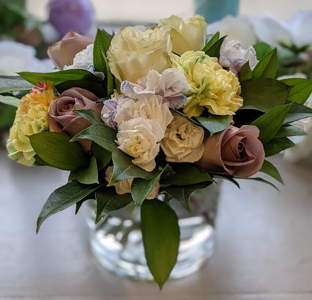 Bouquet of cream and mauve roses with pale carnations in a glass vase
