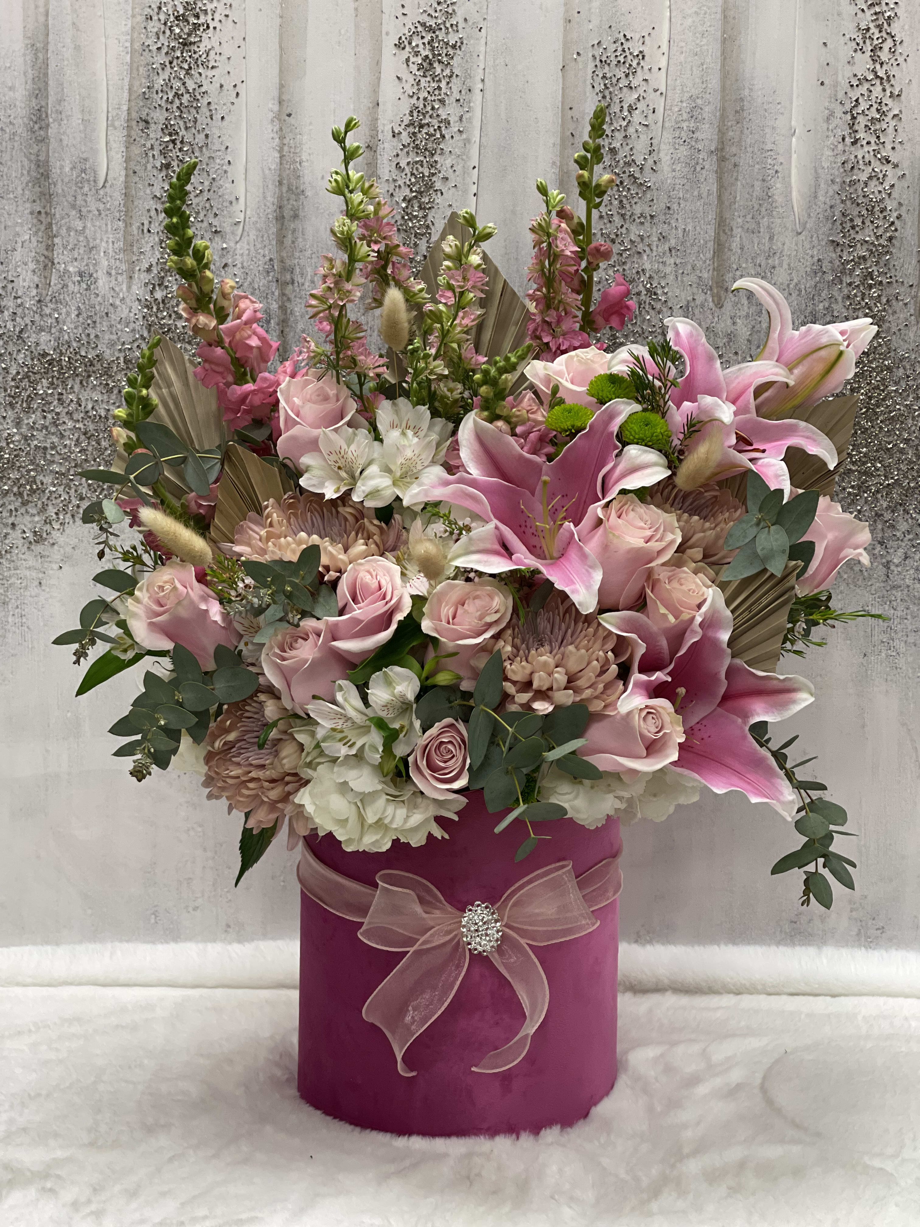 Pink and white floral arrangement in a magenta hat box with a ribbon bow