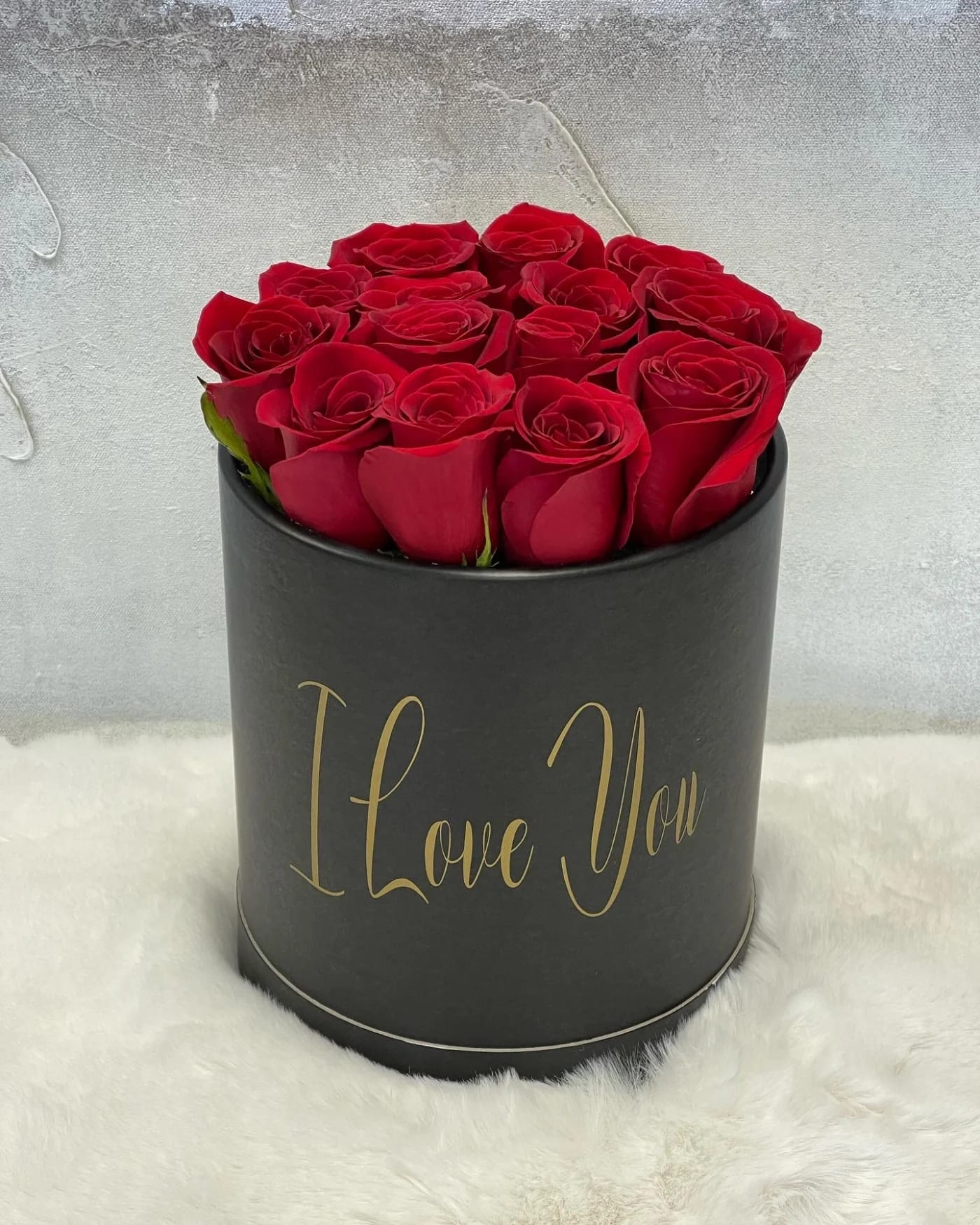 Red roses arranged in a black round box with gold "I Love You" text
