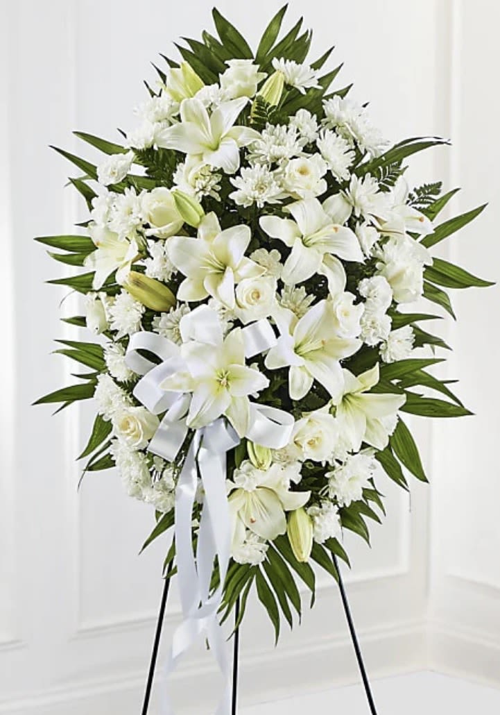 White funeral spray with lilies, roses, and chrysanthemums on a stand