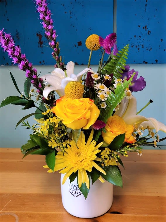 Colorful mixed bouquet in a white vase with yellow, white, and purple blooms