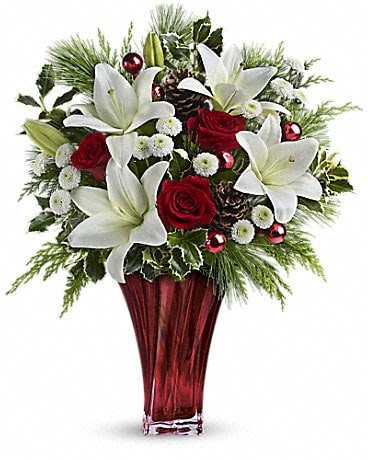 Wondrous Winter Bouquet - Wow them this winter! This gorgeous mix of red roses, snow white lilies and fresh winter greens is arranged in an elegant and gorgeous red blown glass vase. Red roses, white asiatic lilies and white button chrysanthemums are accented with fresh flat cedar, variegated holly, white pine, pinecones and red ornament balls. Delivered in a stunning Love's Passion vase.