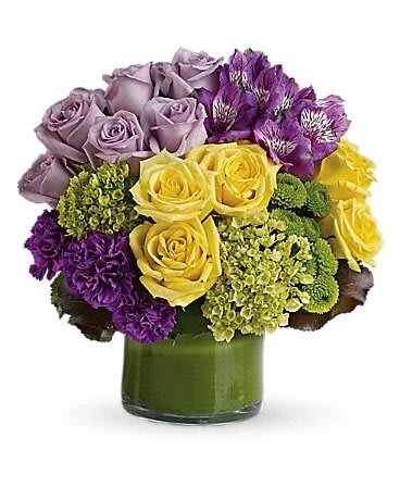 Bouquet of yellow, lavender, and purple flowers in a green glass vase