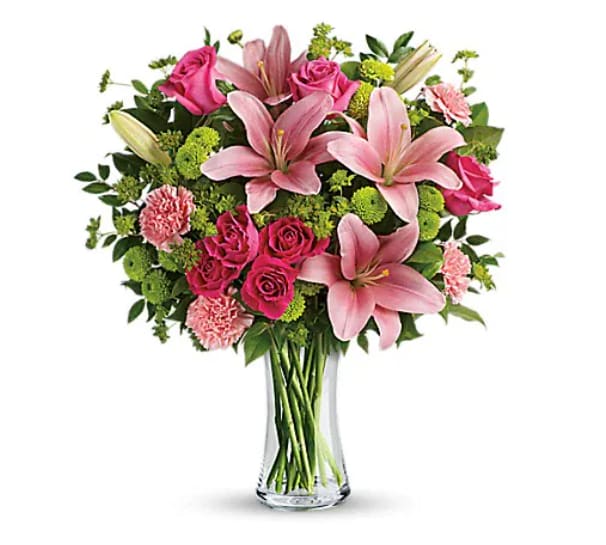 Pink lilies and roses arranged in a clear glass vase