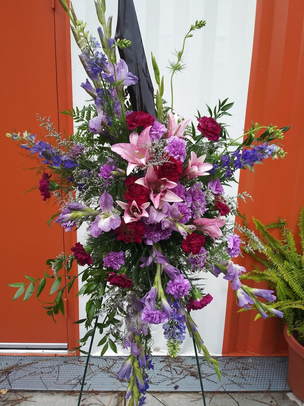 Tall floral spray with pink lilies and purple flowers on a stand