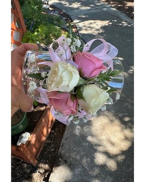 Pink and white rose wrist corsage with small white blooms and pink ribbon on a clear band