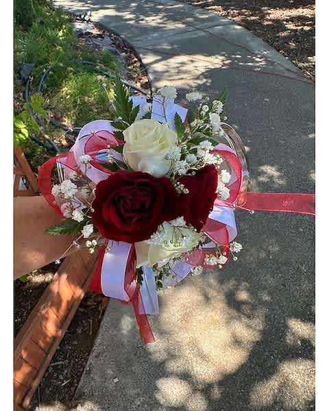 Red and white rose corsage with baby's breath and red and white ribbon on a wrist
