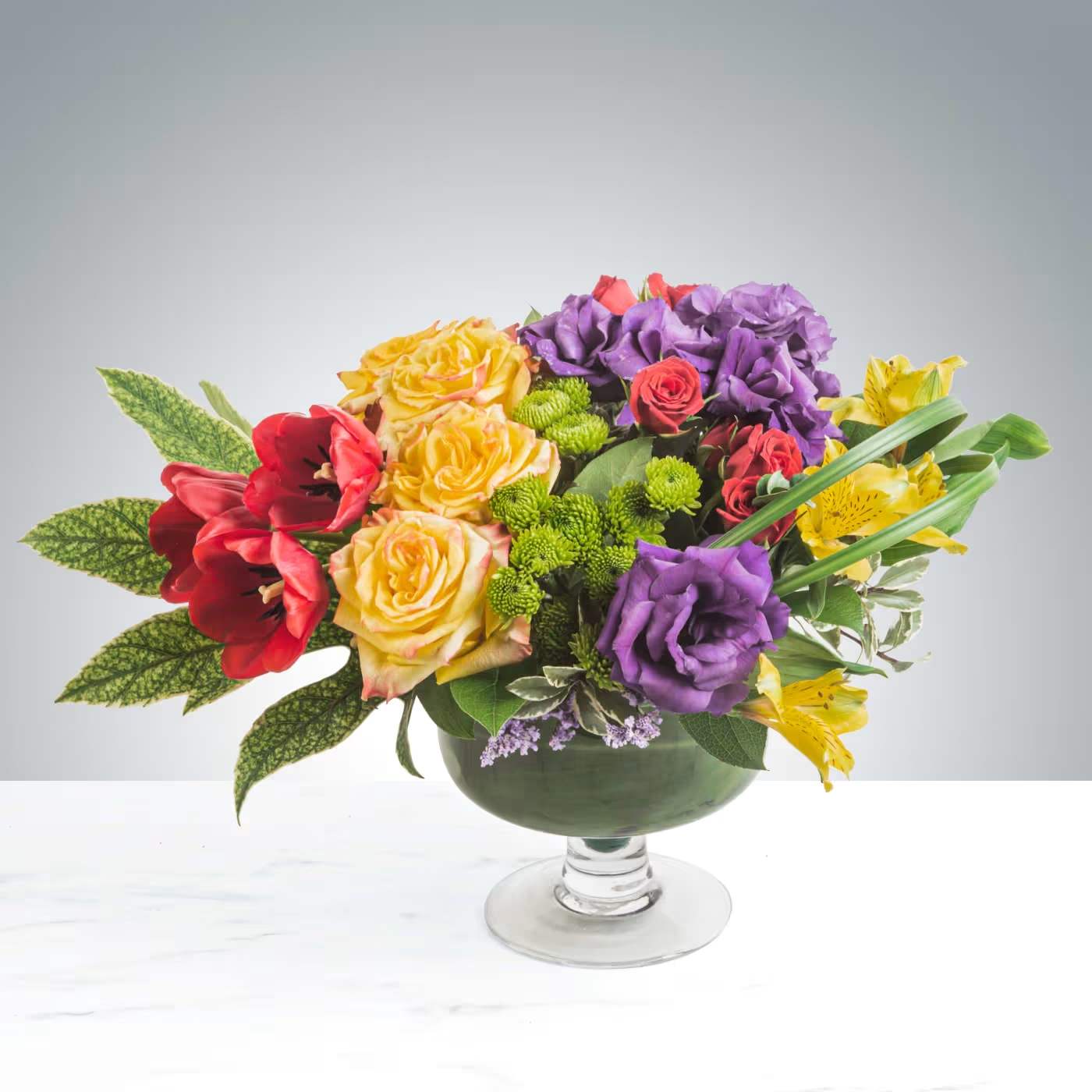 Colorful mixed bouquet in a glass pedestal vase