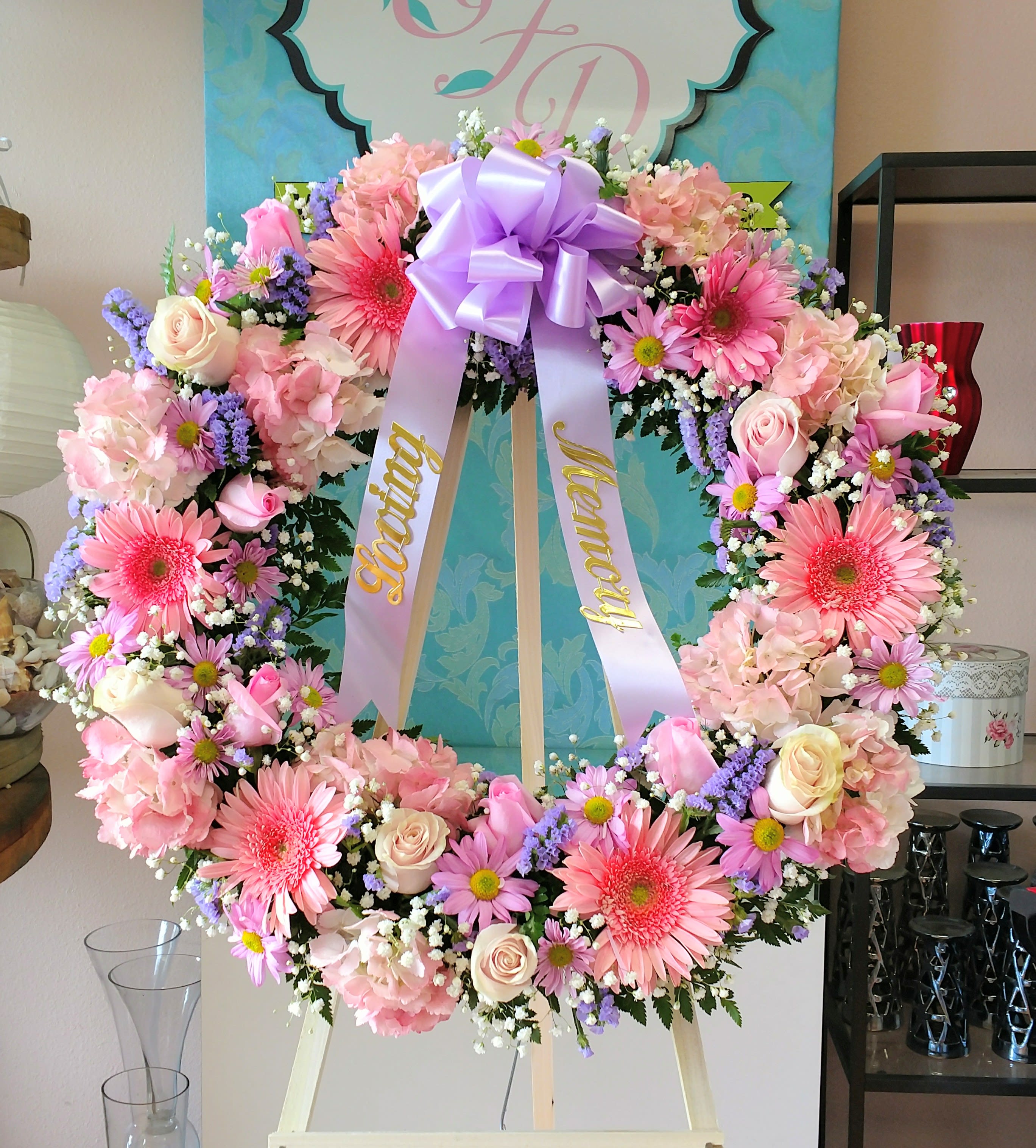 Large pink and lavender floral wreath with a purple bow on an easel