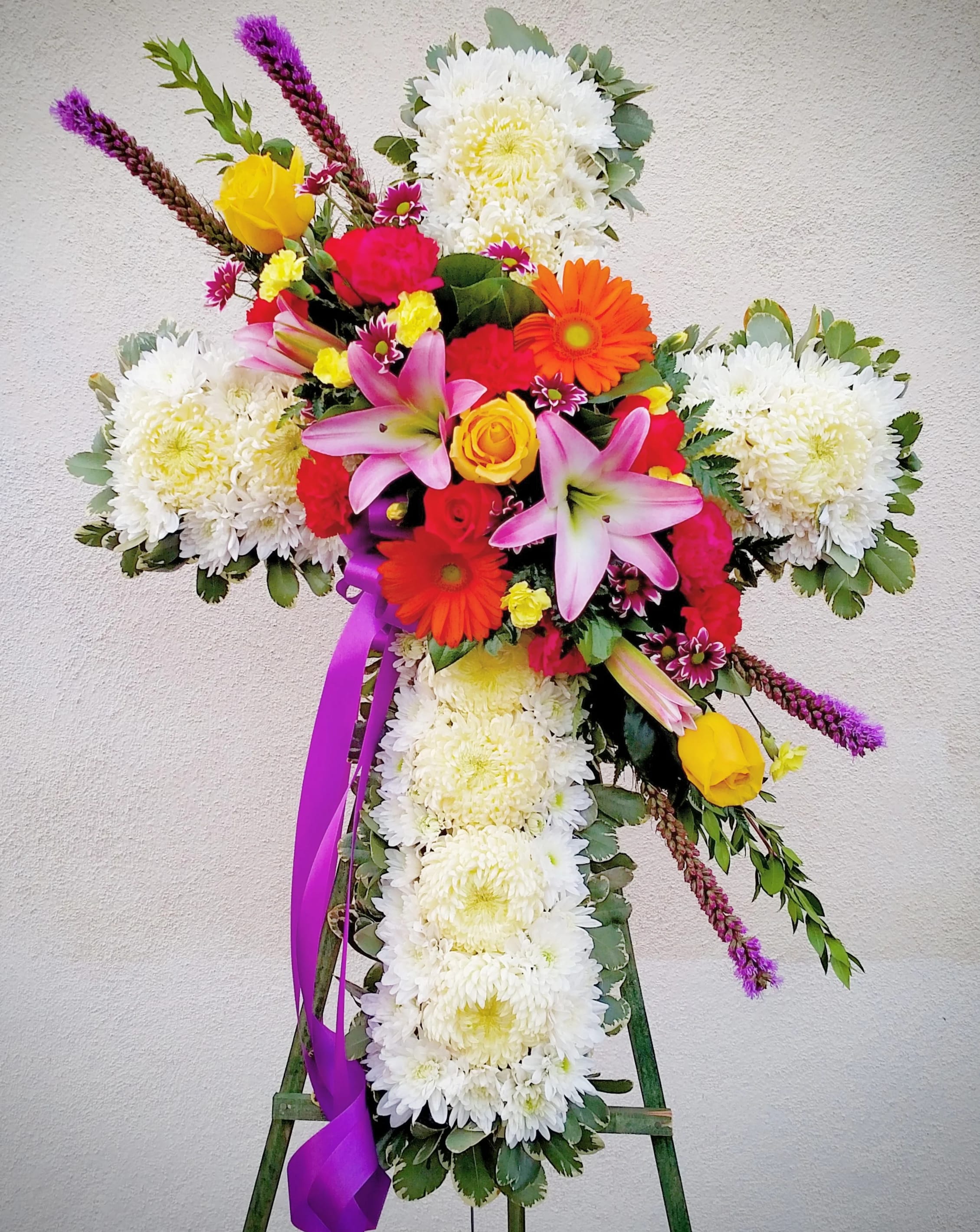 Cross-shaped floral tribute with white chrysanthemums and bright mixed blooms