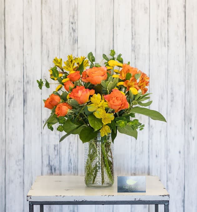 Orange and yellow flowers arranged in a clear glass vase