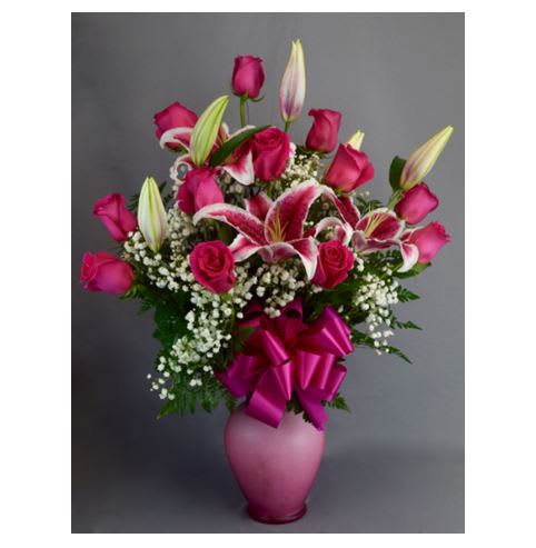 Pink roses and lilies in a pink vase with a ribbon