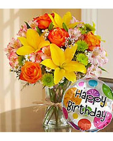 Bright mixed bouquet in a glass vase with a birthday balloon