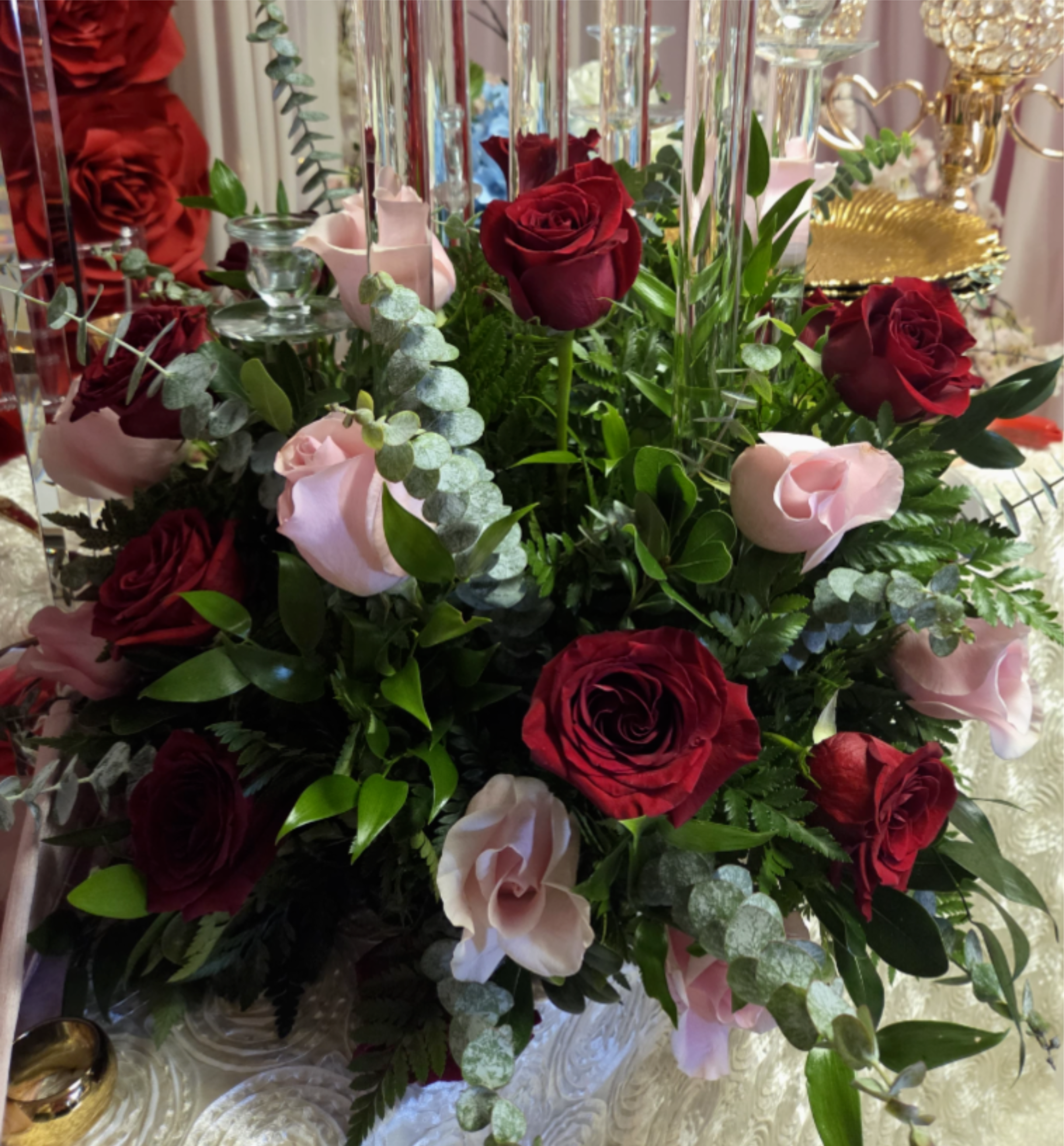 Red and pale pink roses arranged with greenery in a tall centerpiece