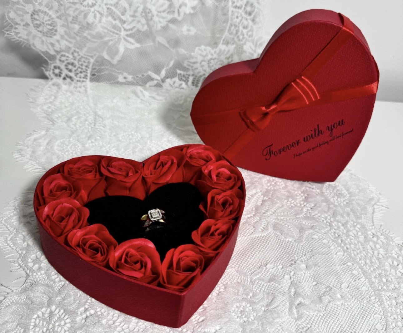 Heart-shaped red gift box with red roses and a ring inside