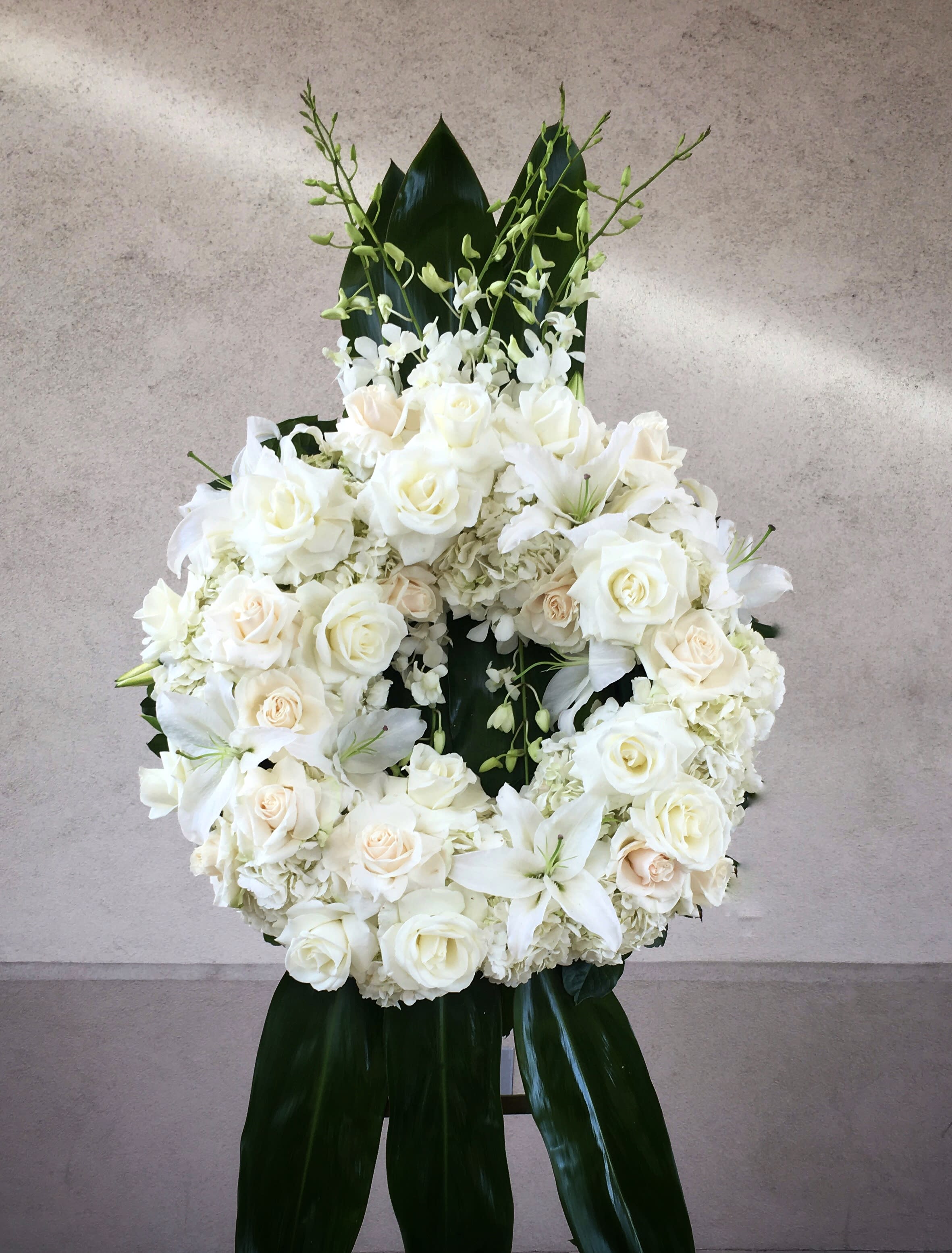 White rose and lily wreath with dark green leaves