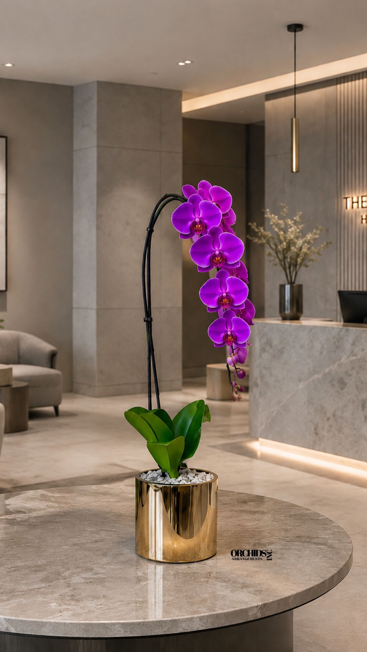 Purple orchid arrangement in a gold pot on a marble table