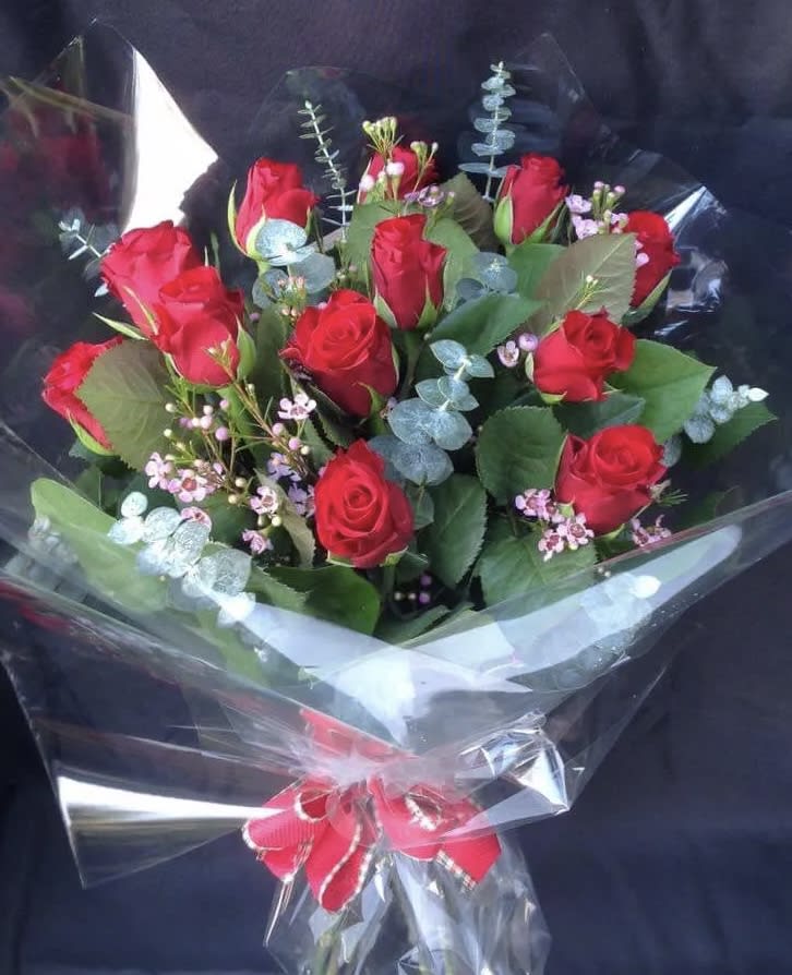 Bouquet of red roses wrapped in clear plastic with a red ribbon