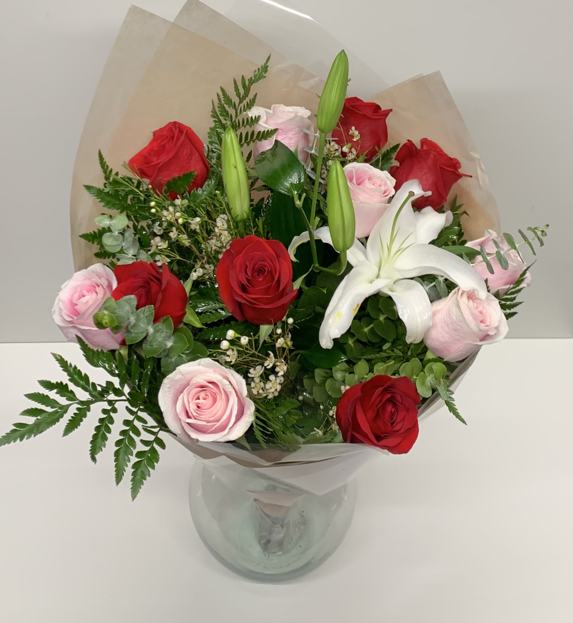 Bouquet of red and pink roses with a white lily in a glass vase