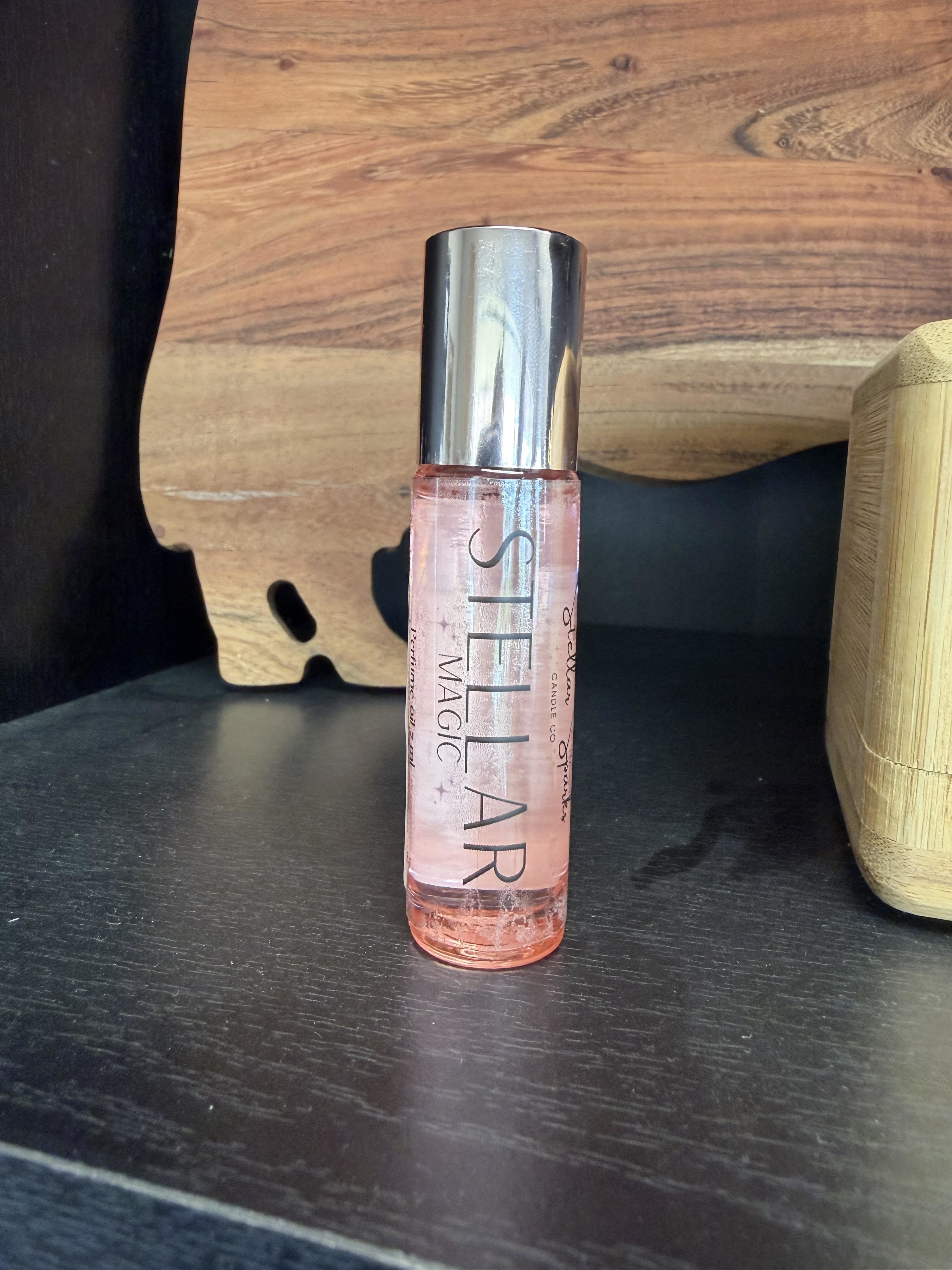 Stellar Magic Perfume - Pale pink perfume in a sleek cylindrical bottle makes a quietly romantic gift for a birthday or "just because" occasion-the kind of present that feels personal and thoughtfully chosen. This perfume bottle-style arrangement reads as an intimate gift for her: delicate, feminine, and everyday-elegant, ideal for celebrating a friend, partner, or someone who cherishes small luxuries.  The clear glass bottle holds a soft blush liquid and is topped with a reflective silver cap; the label reads "SHELLAR MAGIC," giving it a boutique, handcrafted vibe. Compact and simple in design, it's perfect for tucking into a gift bag or pairing with a single stem or note. Recommend as a small-gesture present to make the person you're thinking of feel cherished-no fuss care, ready to gift as shown.