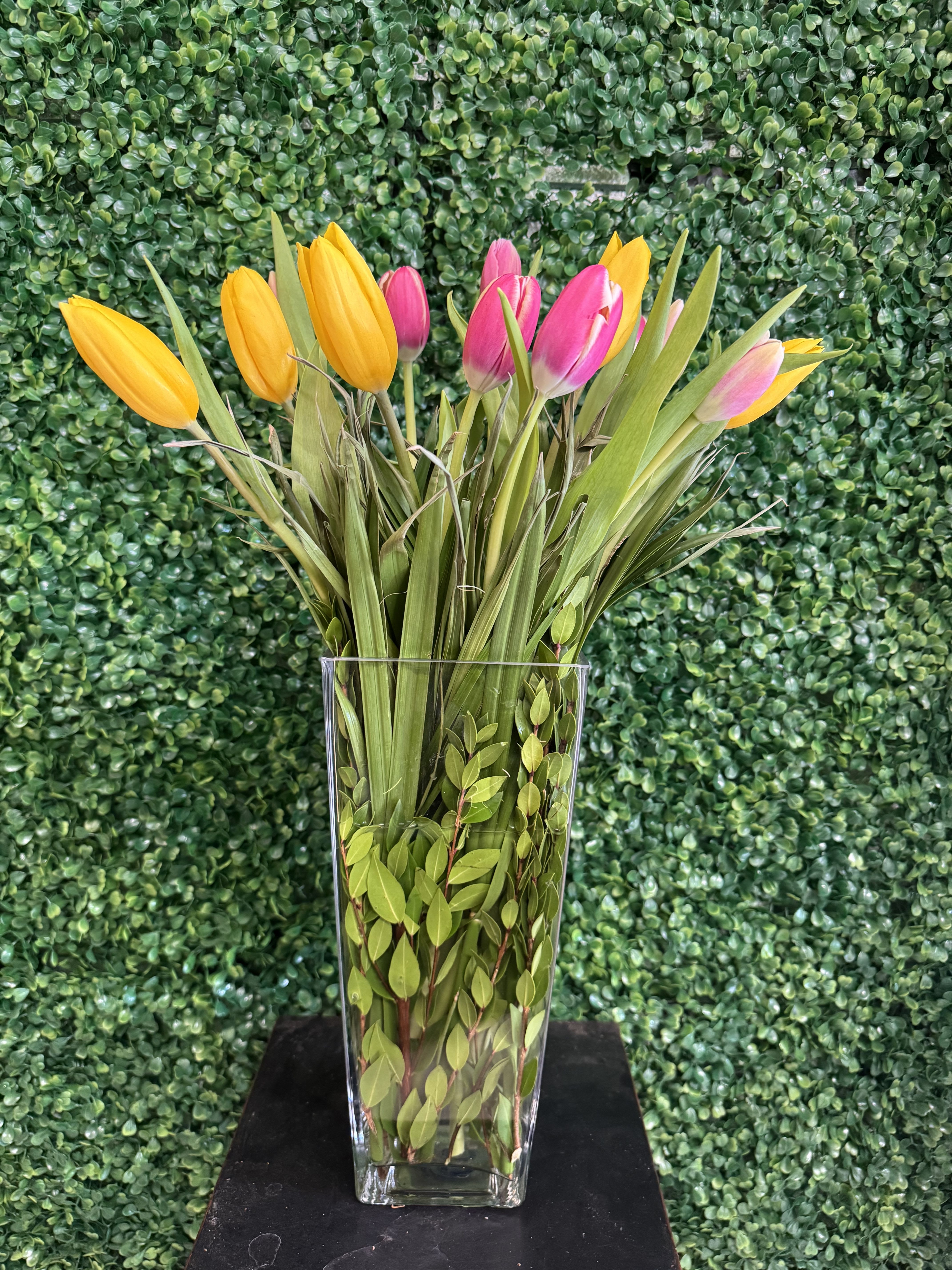 Yellow and pink tulips in a clear glass vase