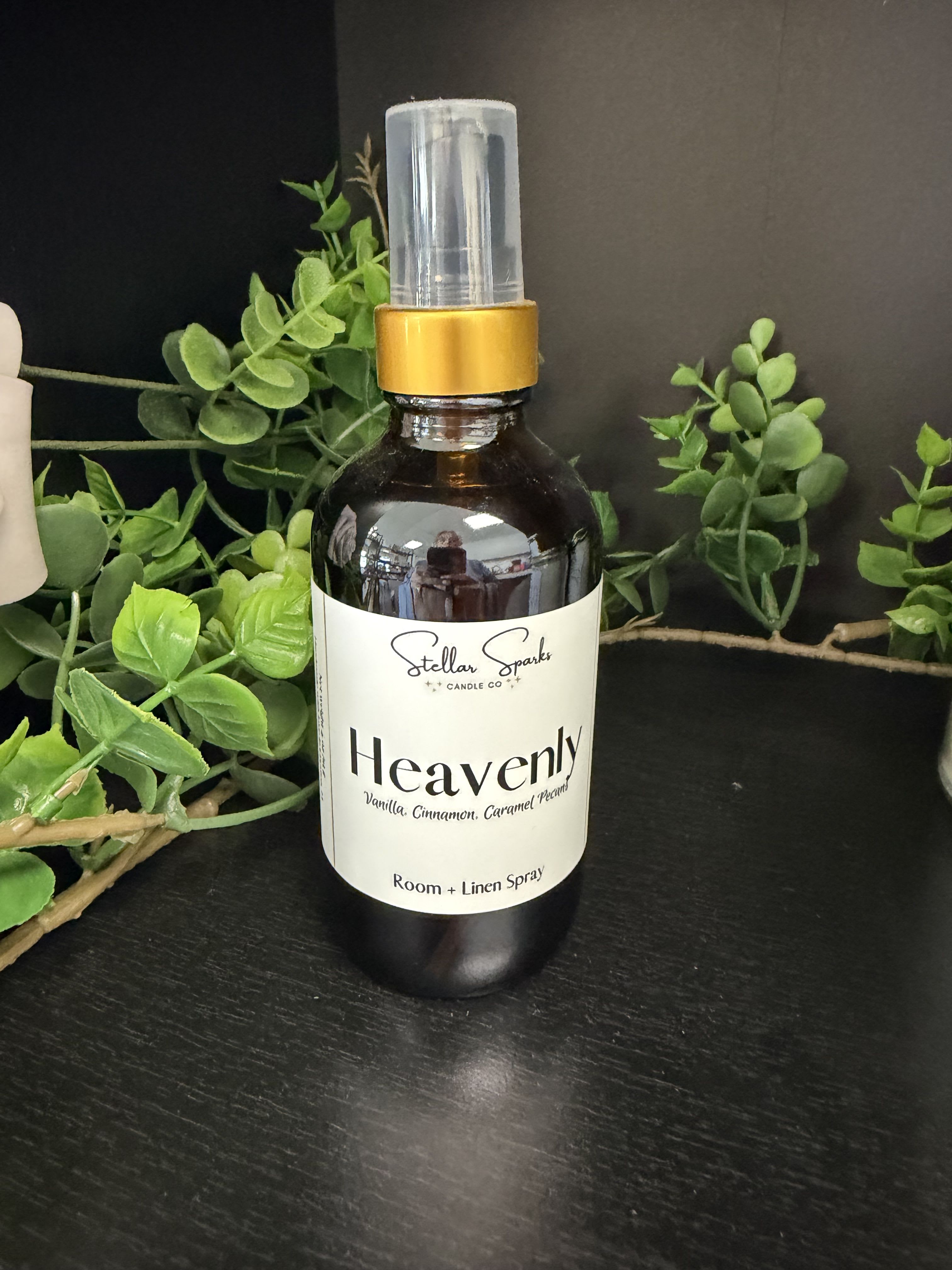 Heavenly Room Spray - Warm vanilla, cinnamon and caramel notes promise to make any space feel like a comforting embrace-perfect as a housewarming gift or a thoughtful flourish for a cozy bedroom or living room. This room and linen spray is presented as a dark amber bottle with a white label and gold collar, the word "Heavenly" front and center; the look is clean and understated, making it an elegant choice for someone who appreciates simple, cozy home fragrances rather than floral scents.  The spray comes with a clear plastic cap and a handy bottle that pairs beautifully with dark, neutral decor or a shelf of books and greenery. Fragrance highlights include vanilla, cinnamon, caramel and pecan for a warm, gourmand aroma that lifts linens and soft furnishings without overpowering a room. Gift it to someone settling into a new home, to mark a special occasion like a birthday or anniversary, or to let a loved one know you're thinking of them-she'll feel genuinely comforted every time the scent returns.