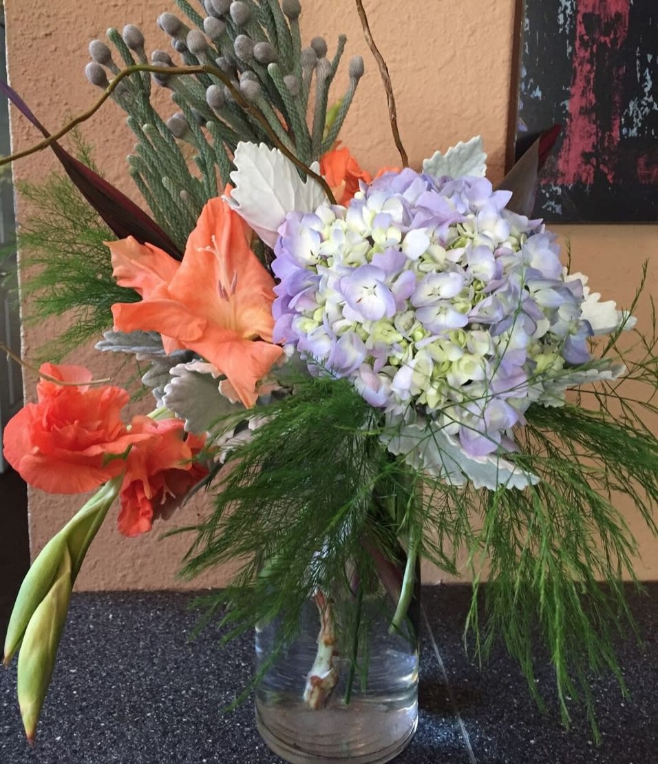 Bouquet of lavender hydrangea and orange lilies in a glass vase